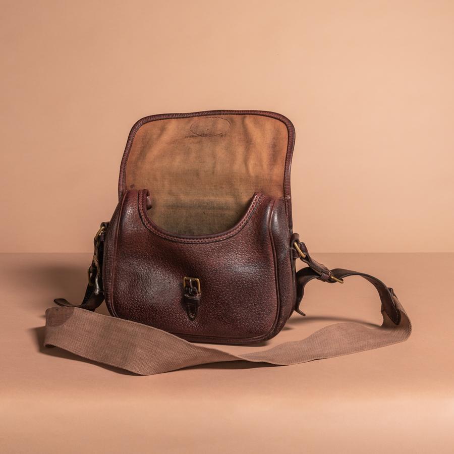 A superb leather cartridge bag designed to carry 100 shells; Circa 1920. Good quality; sturdy leather and brass fittings with canvas and leather strap. Not too much wear inside or out. Stamped on the back; 100 - Warranted Pigskin. Original embossing