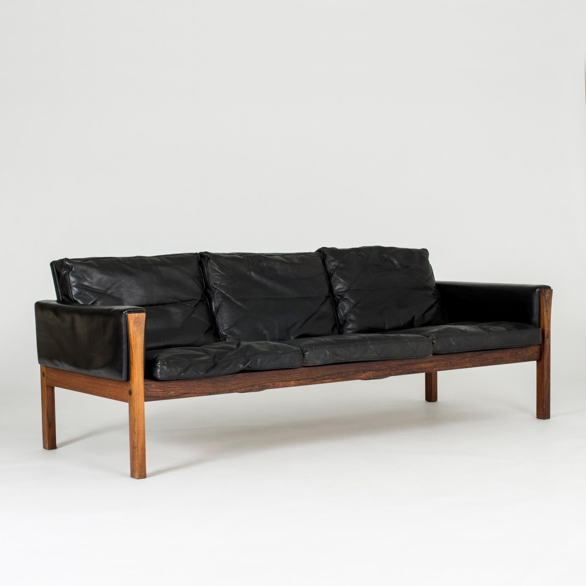 Elegant, luxurious “CH 163” sofa by Hans J. Wegner, made with a rosewood frame and black leather upholstery. Nice details of circles inlaid into the wood and leather folded over the armrests. Nicely aged leather.