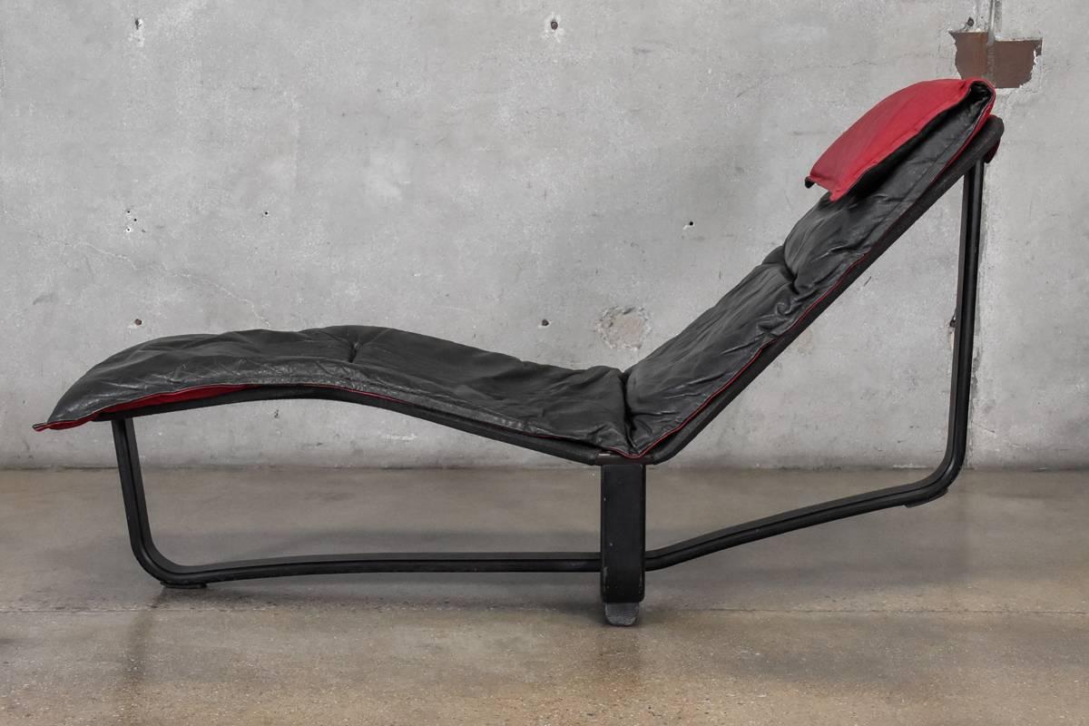 Minimalist chaise lounge designed by Ingmar and Knut Relling for Westnofa. Features an ebonized bent wood frame with black leather cushion and contrasting red fabric headrest. The lounge can be shifted form a more upright position to a more reclined