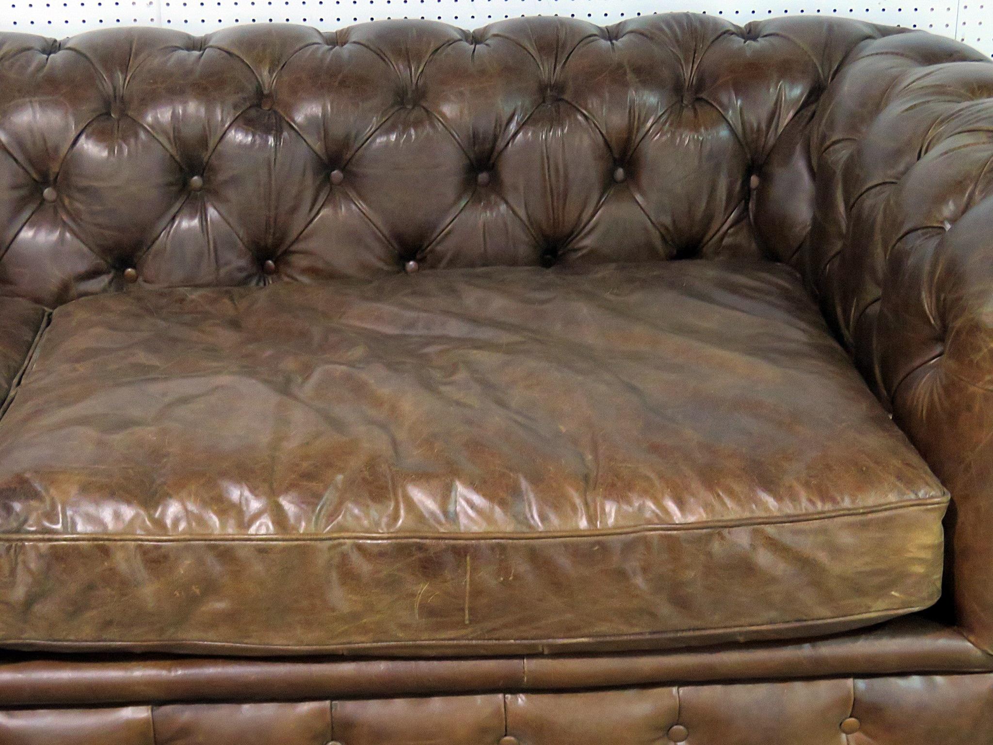 Tufted distressed leather Chesterfield sofa on casters.