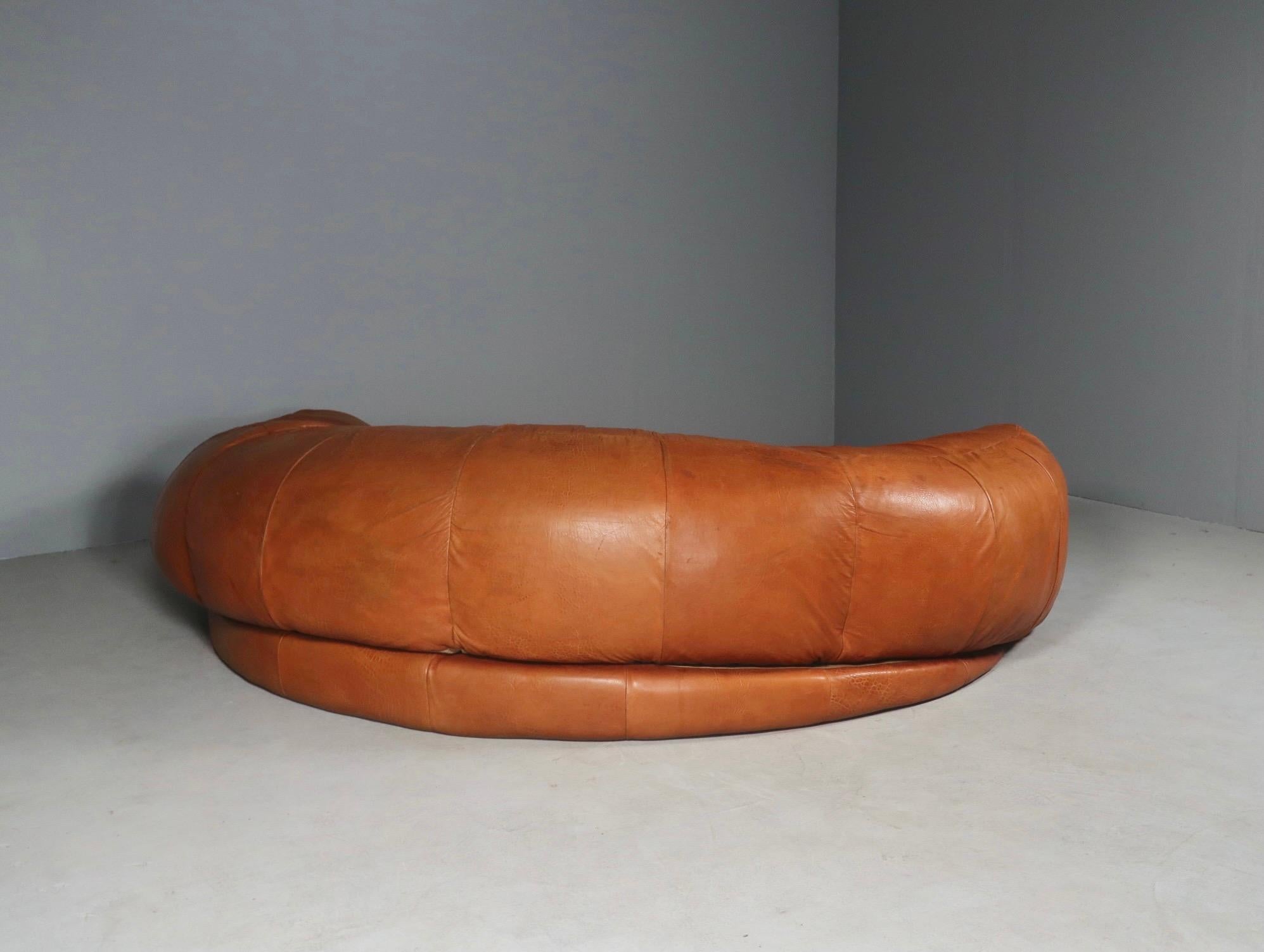 Stunning leather sofa by Raphael Raffel for Honore, Paris. Made to order back in the 1970s and seldom available for purchase. Saddle leather sofa in the shape of a giant croissant. Good vintage condition and gorgeous coloring.