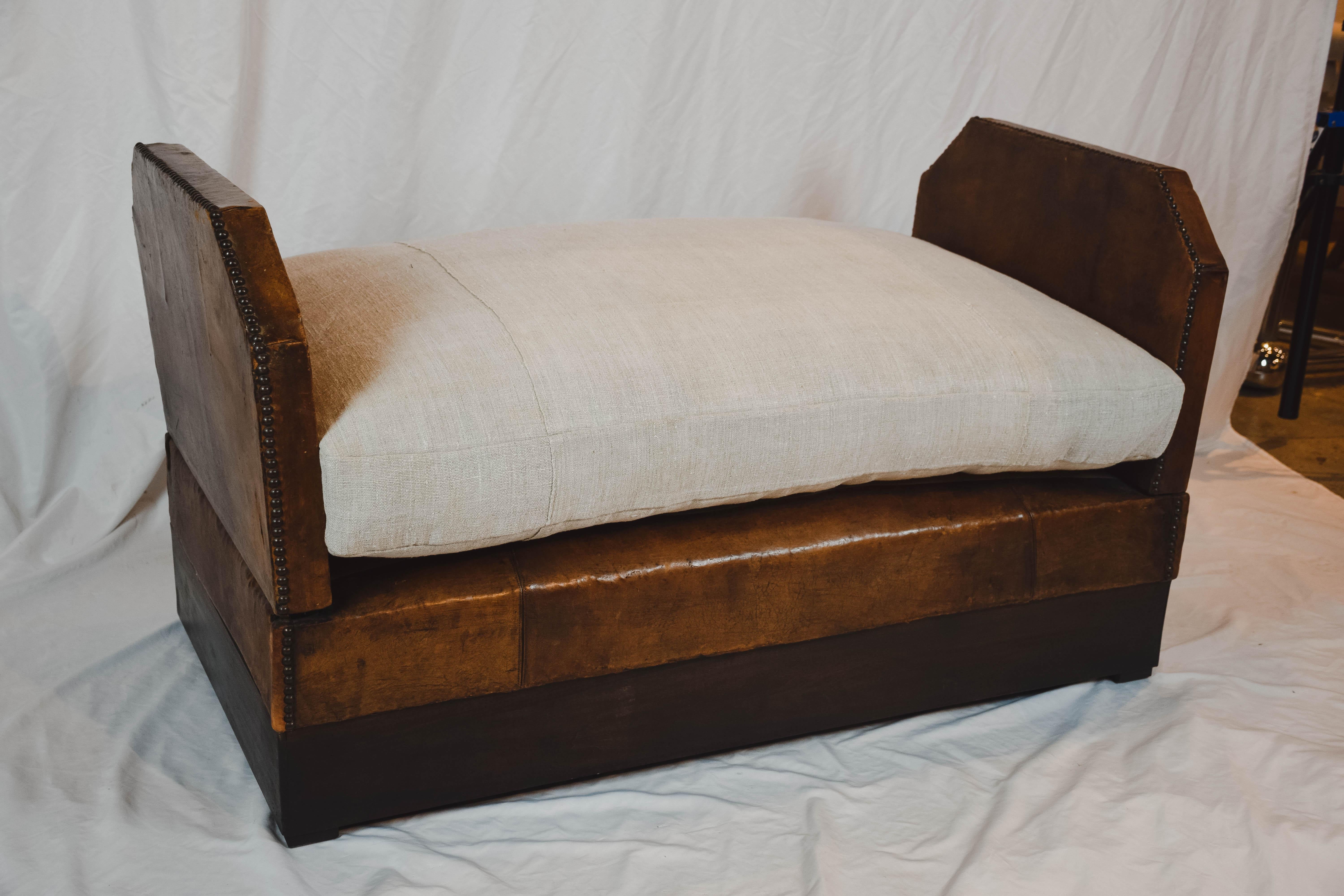 An antique leather daybed from France that is as versatile as it is unique. With both sides up it is a small settee while with one of the drop sides down and the other at an angle it becomes a chaise. Dropping both sides down into its fully opened