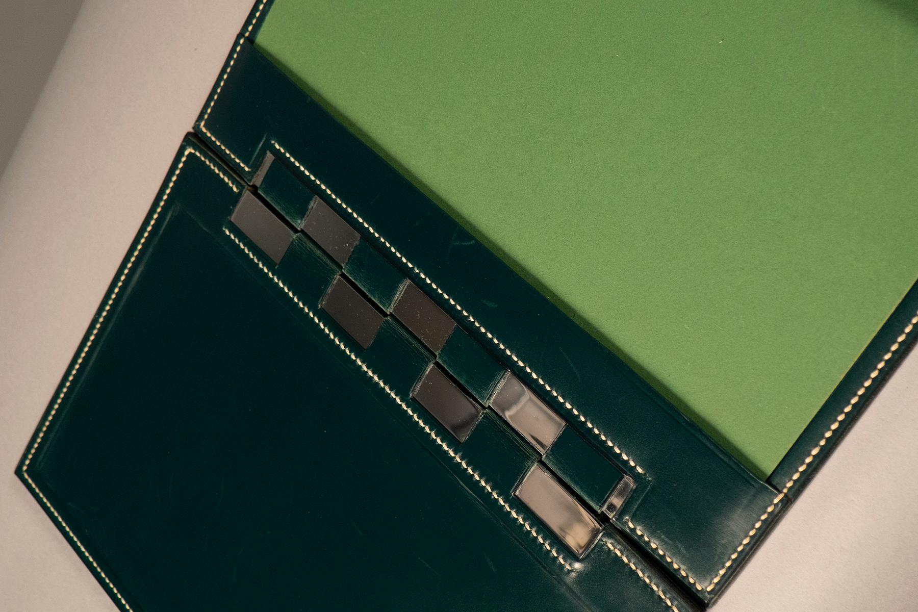 Saddle-stitched green/black leather desk set consisting of a writing pad, storage box and a blotter. Stamped “Hermes”

Writing Pad: 18” x 13.5” 
Box: 9” x 5” 
Blotter: 6” x 3.5” by 4” high.