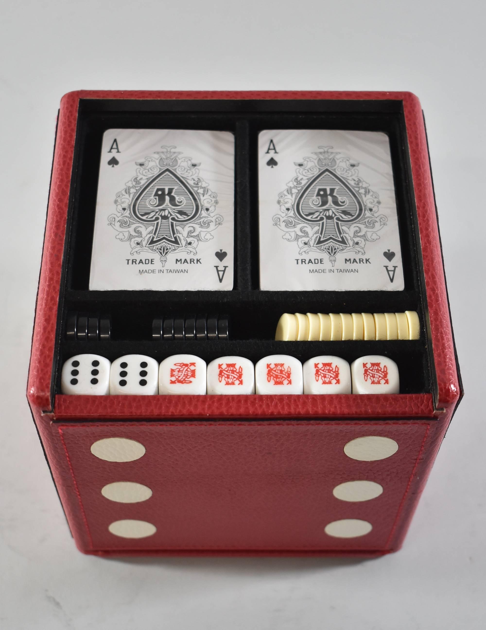 Une boîte de jeu inhabituelle sous la forme d'un dé. La boîte en cuir rouge comporte deux panneaux coulissants qui laissent apparaître les pièces du jeu (cartes:: dés:: dominos:: jetons:: etc.). Marqué Bergdorf Goodman:: made in Italy sur le dessous.