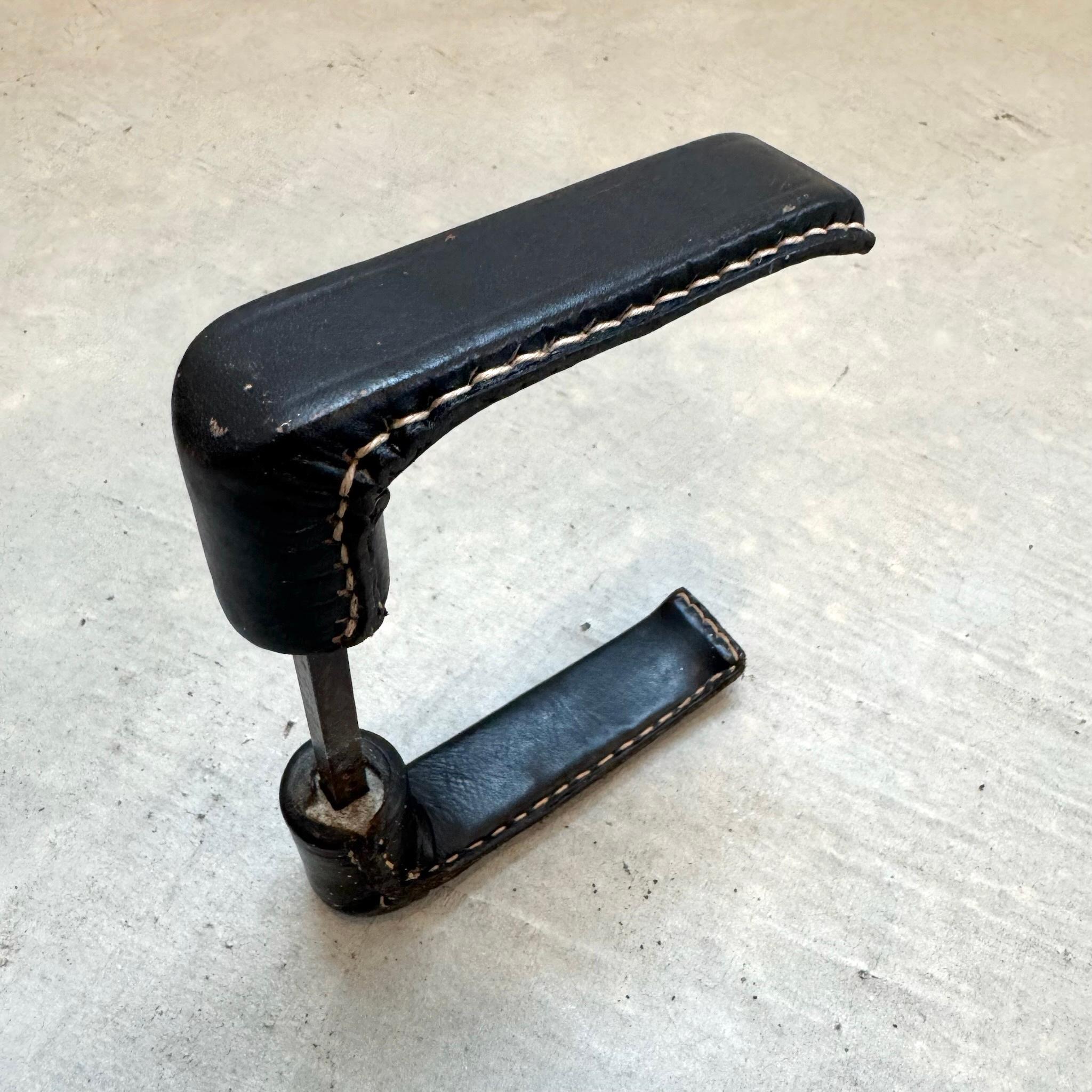 Une belle poignée de porte en cuir à deux faces du designer français Jacques Adnet. Deux leviers en fer sont enveloppés de cuir noir, et une tige de connexion est attachée à l'un d'eux. Comme de nombreuses pièces du créateur, elles présentent les
