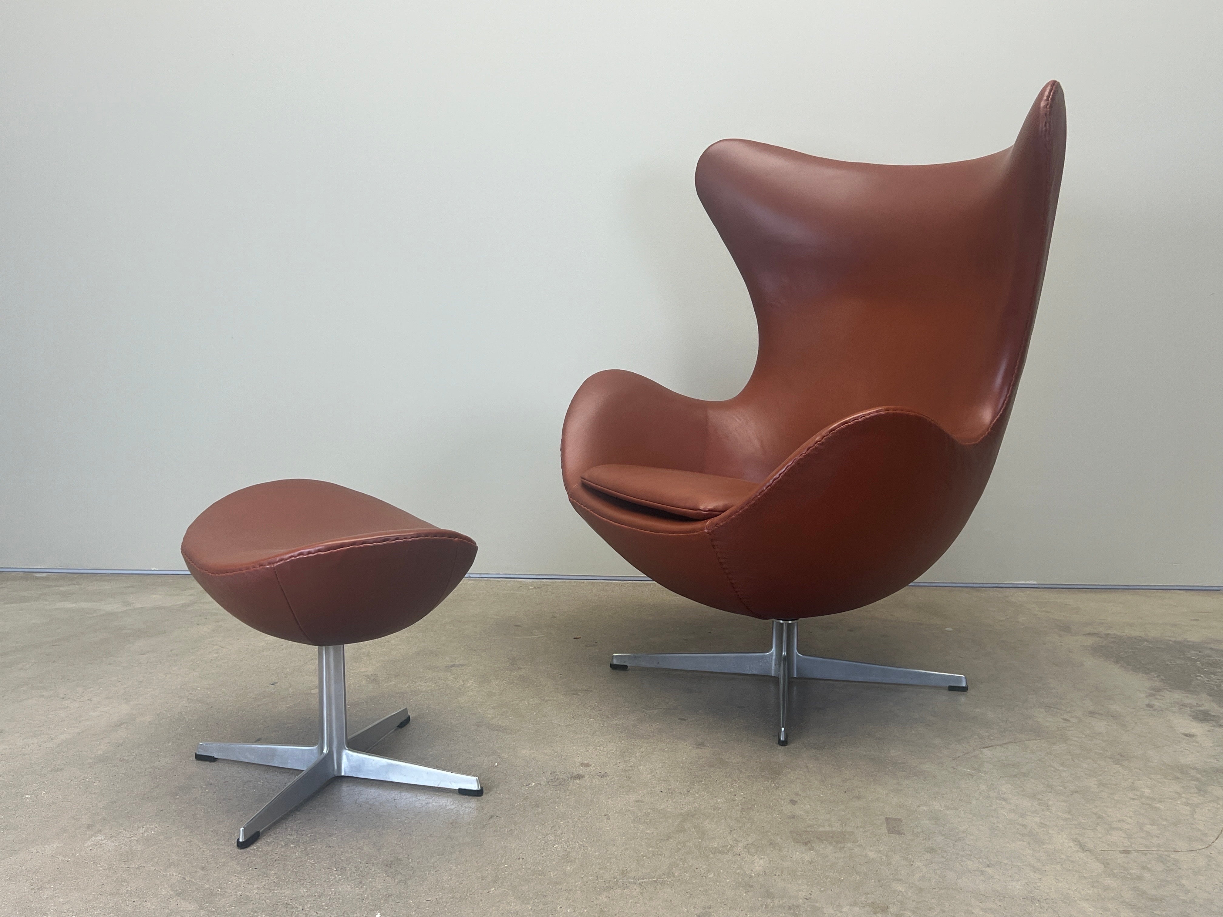 An egg chair and ottoman designed by Arne Jacobsen for Fritz Hansen reupholstered in cognac leather. 
