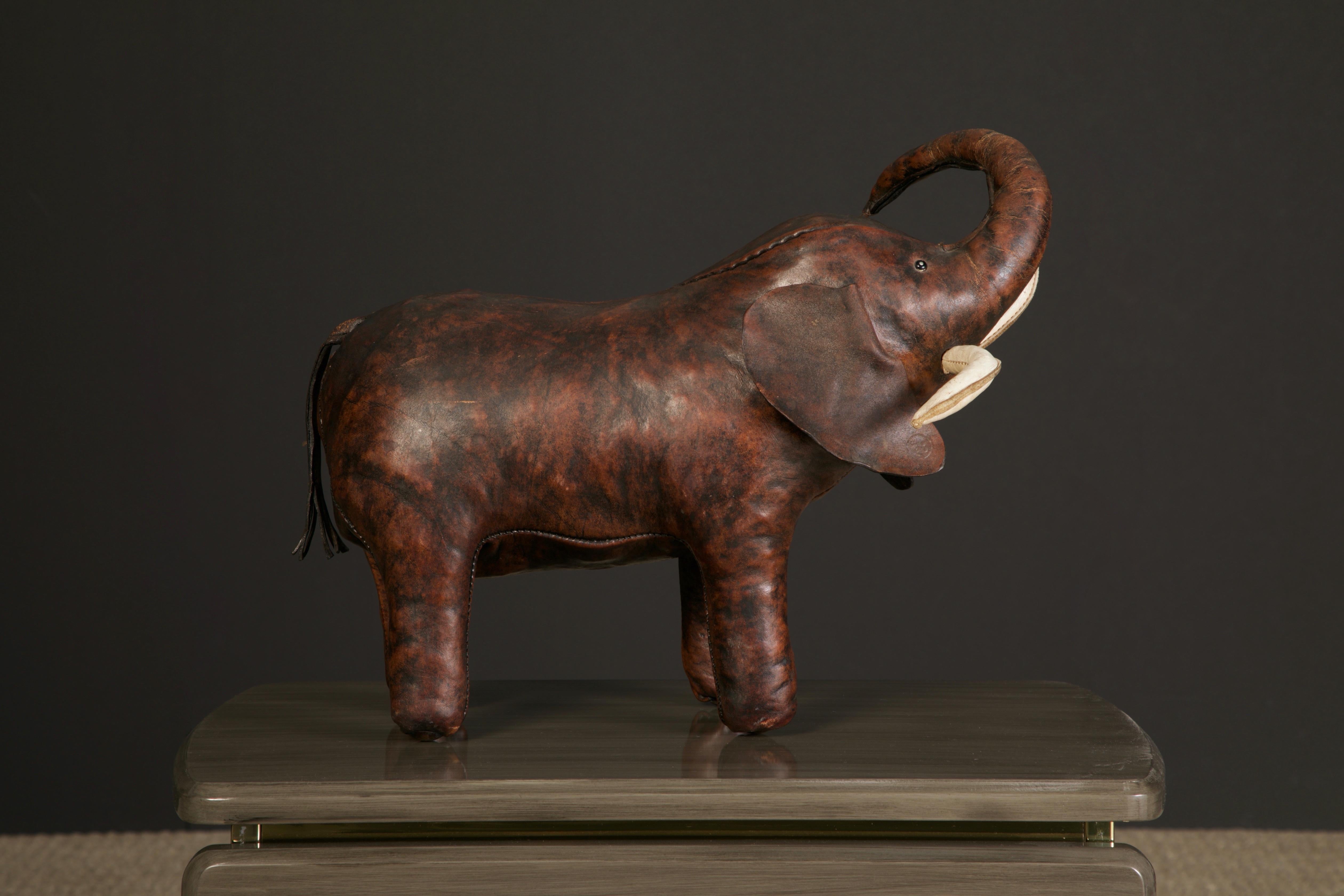 A wonderful collectors example of an original leather elephant footstool by Dimitri Omersa for Abercrombie and Fitch, circa 1963. This example is signed with the circle 'A&F CO' embossed stamp under one ear, has the early nail heads under its feet,