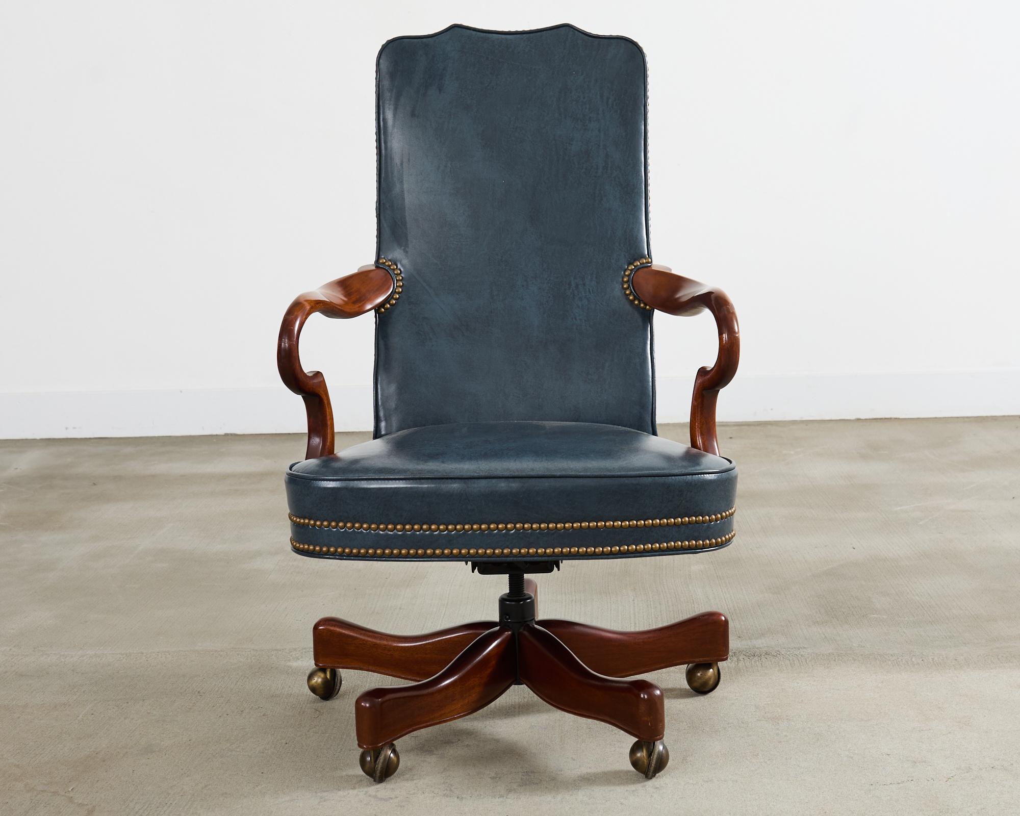 Opulenta silla basculante y giratoria de oficina ejecutiva de caoba y cuero, de estilo georgiano, atribuida a Hancock & Moore. La silla presenta un radiante armazón de caoba con una cresta de doble pico. El marco está cubierto con una cresta de