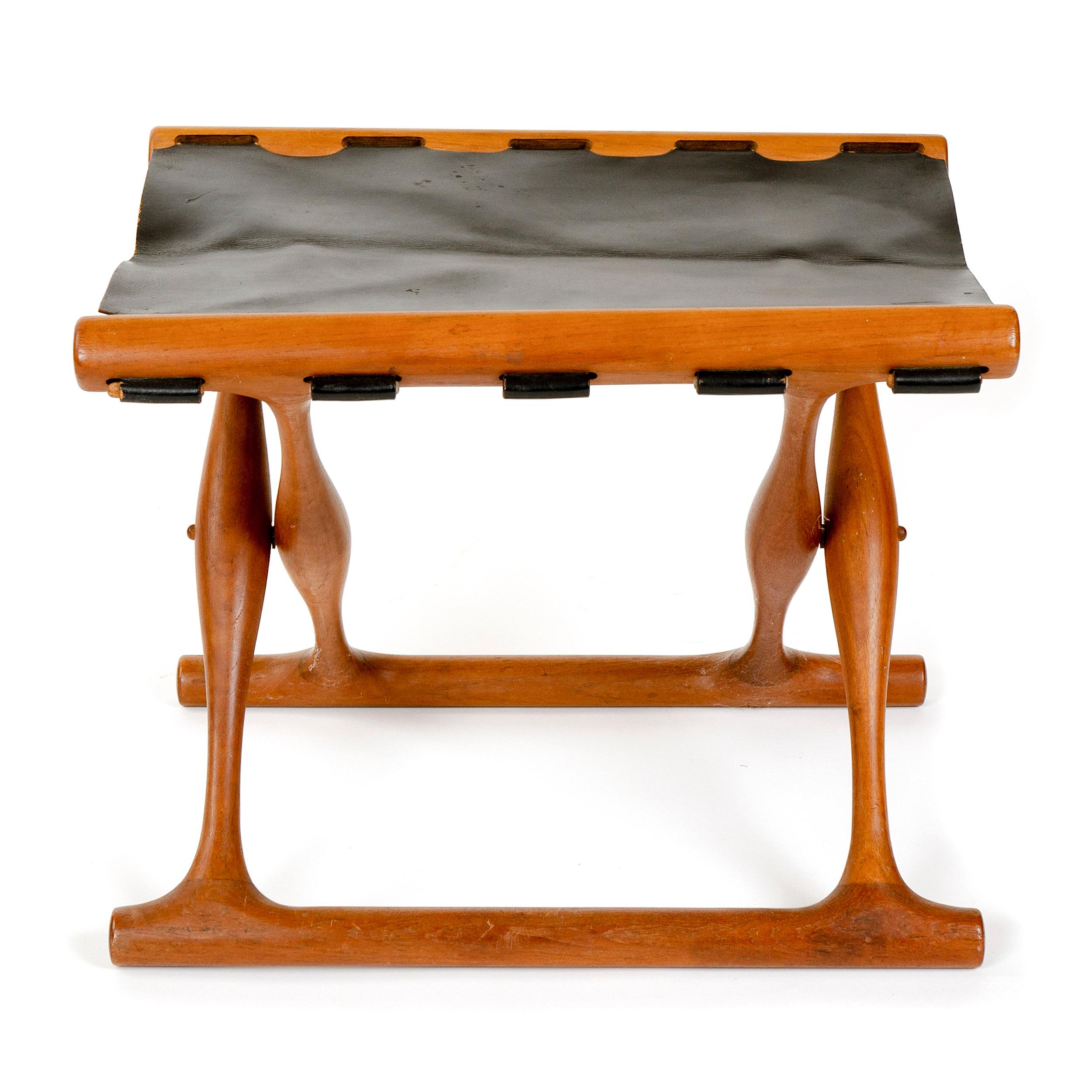 A teak folding stool with a black leather sling seat. Famed copy of oldest existing piece of furniture in Scandinavia.