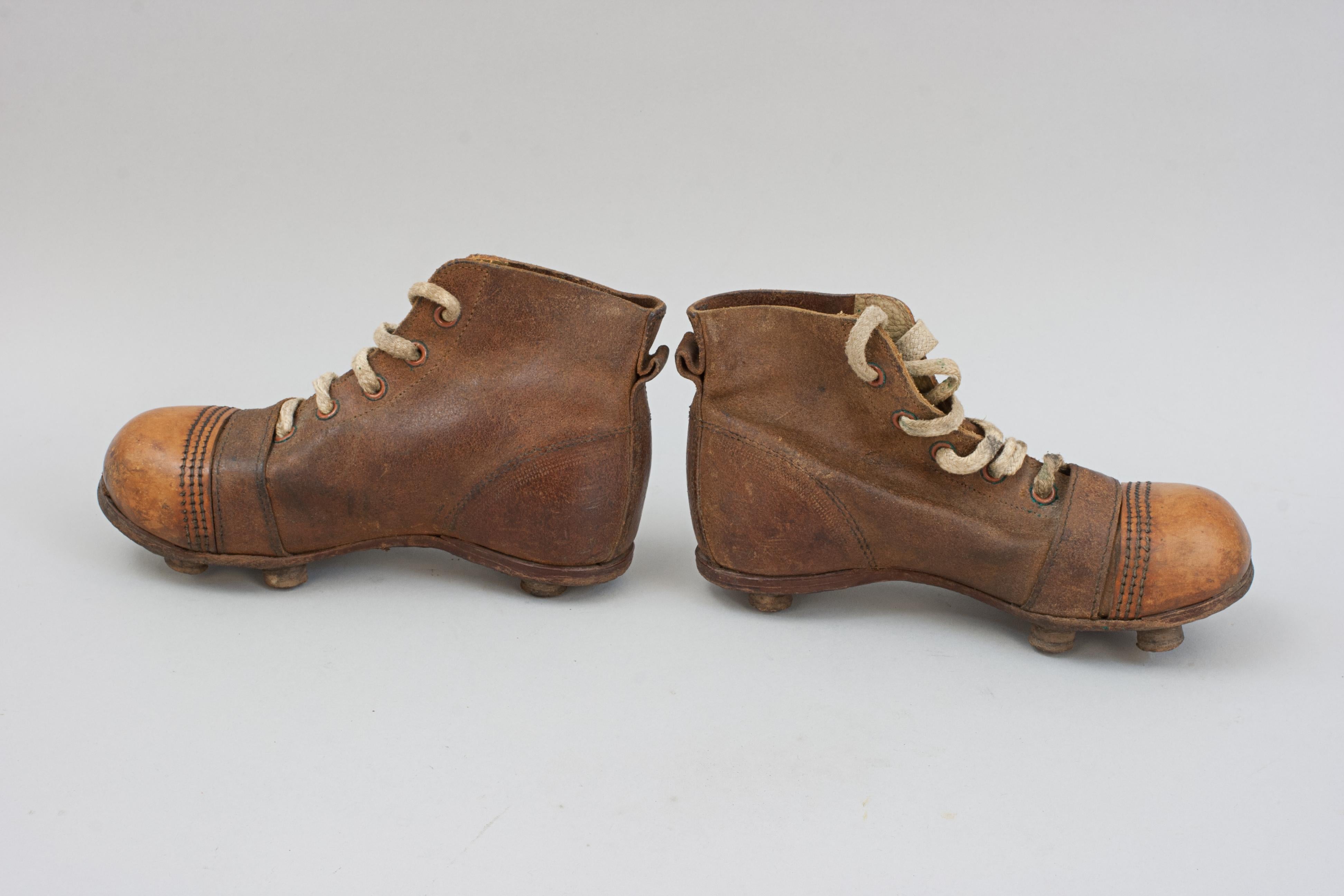 Par vintage de botas de fútbol infantiles de cuero.
Este encantador par de botas de fútbol (soccer/rugby) infantiles de principios del siglo XX es un llamativo ejemplo de ropa deportiva de época. Fabricadas íntegramente en piel, incluida la suela,