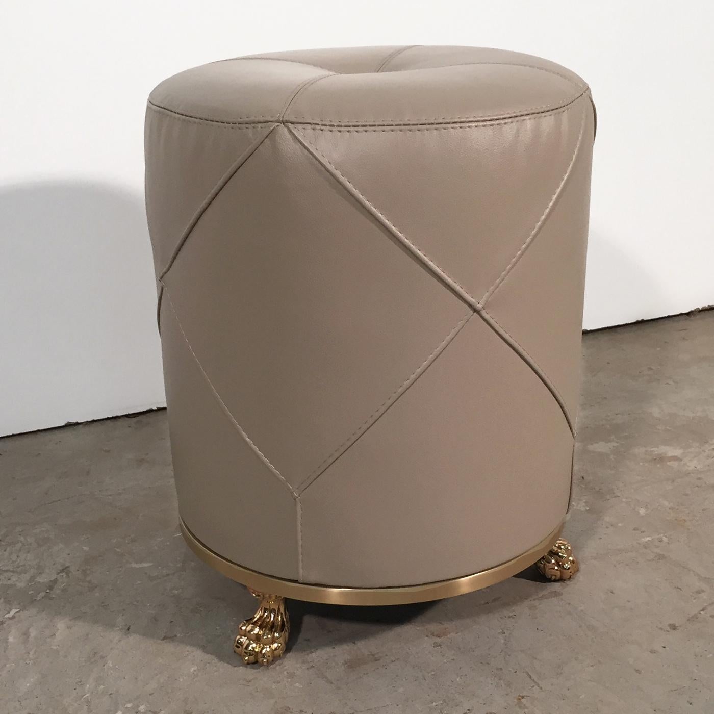 This stylish footstool fuses old with new, drawing inspiration from vintage designs. Its solid wood structure is topped with a rubber cushion, fully upholstered in soft leather with raised rhombus stitching. Decorative brass feet and glossy brass