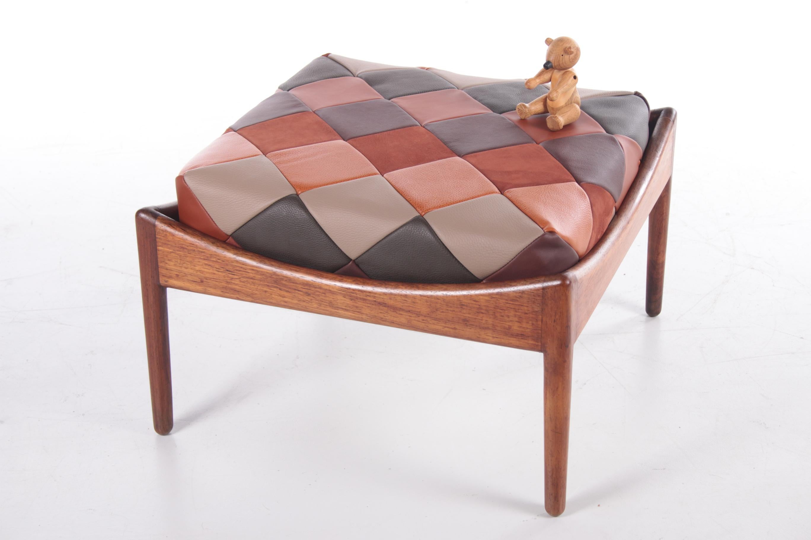 Leather footstool designed by Kristian Solmer Vedel for Søren Willadsen Møbelfabrik in 1963. The stool has a teak wooden frame and a seat of leather in different shades. 

Considering its age this hocker is in very good condition, the cushion is