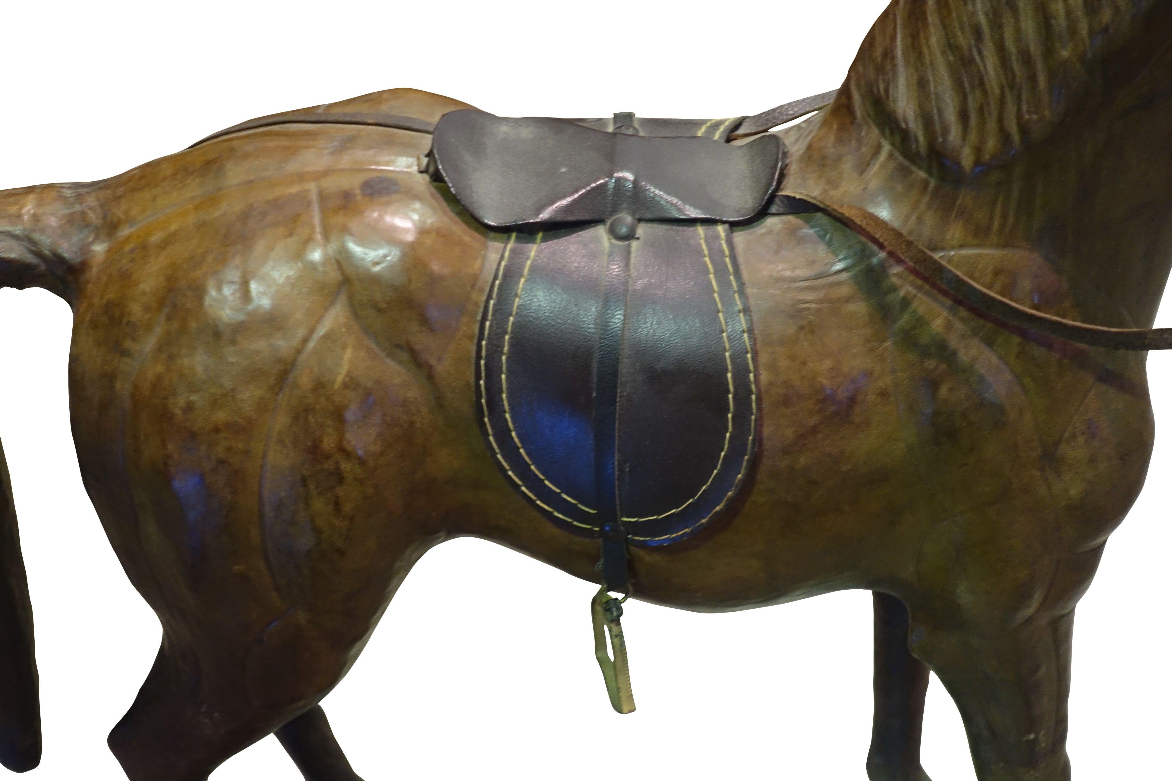 This figure of a wooden horse is completely covered in brown leather.
Exacting details of the decorative saddle and reins.  The green glass eyes are a welcome surprise against the dark brown body with black accents.
Sculpted muscle details enhance