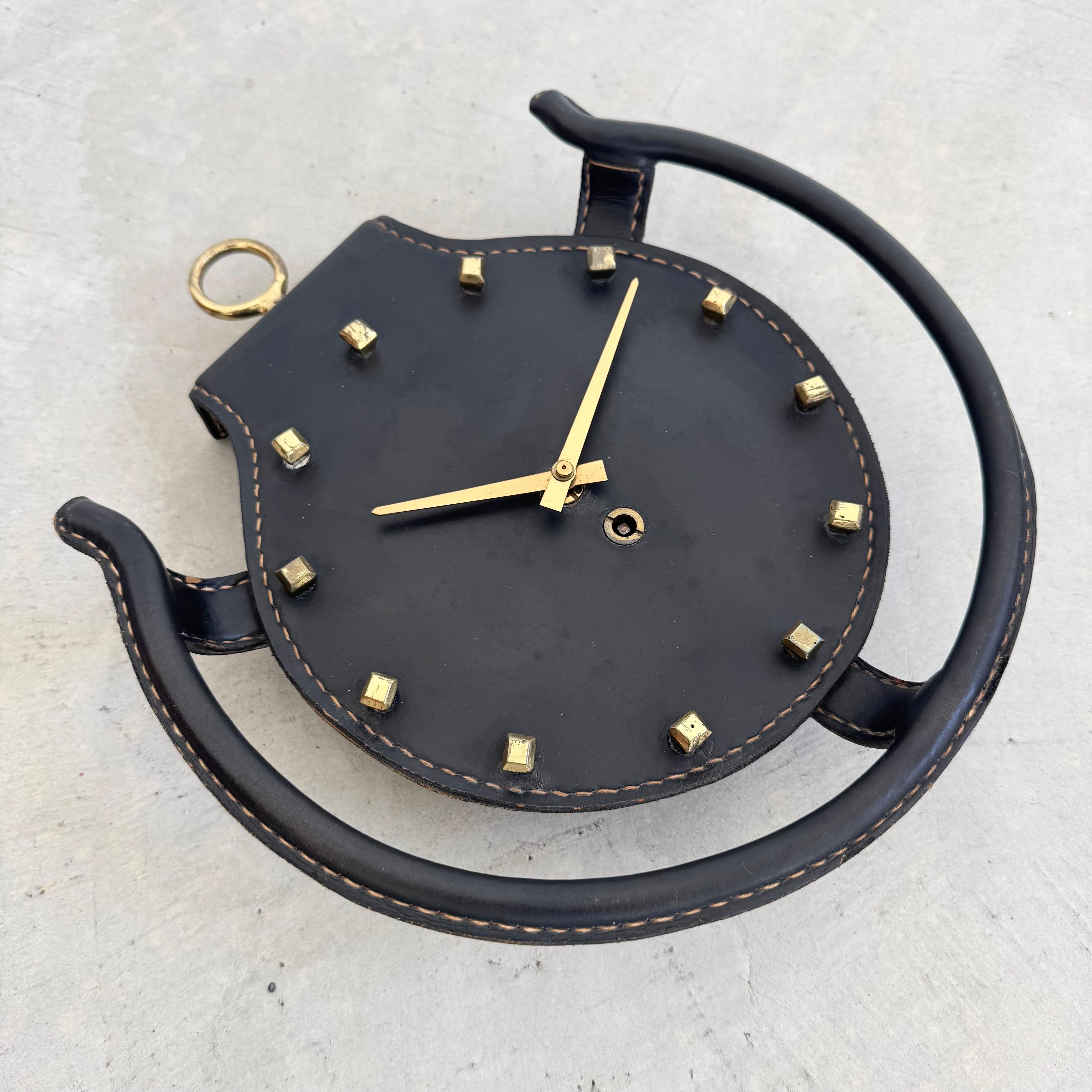Añade un poco de intriga a tu casa u oficina con este bonito reloj de pared en piel de silla de montar negra. Con herrajes de latón y pespuntes en contraste, quintaesencia del estilo refinado de Jacques Adnet. Doce tachuelas rodean las manecillas