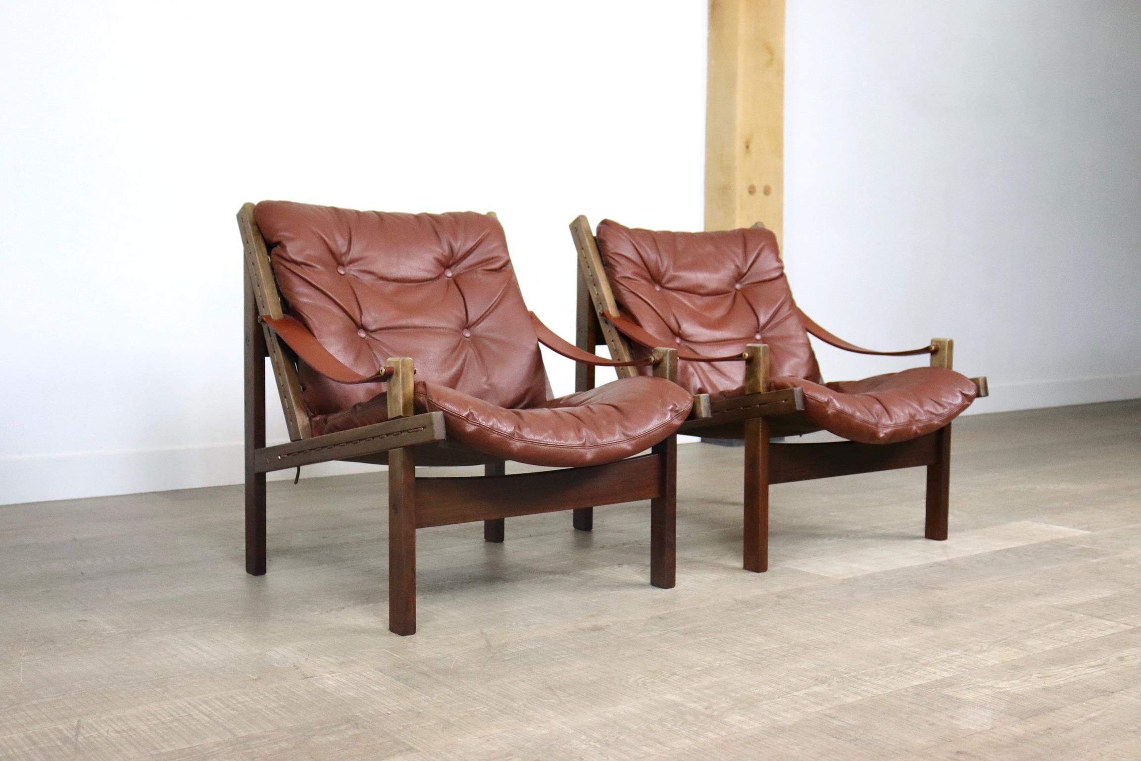 Beautiful pair of leather hunter chairs by Torbjørn Afdal for Bruksbo, Norway 1960s. Oak frame, brown canvas seat with cognac padded leather cushions and harness leather armrests. The canvas is stretched between the frame with a cord.