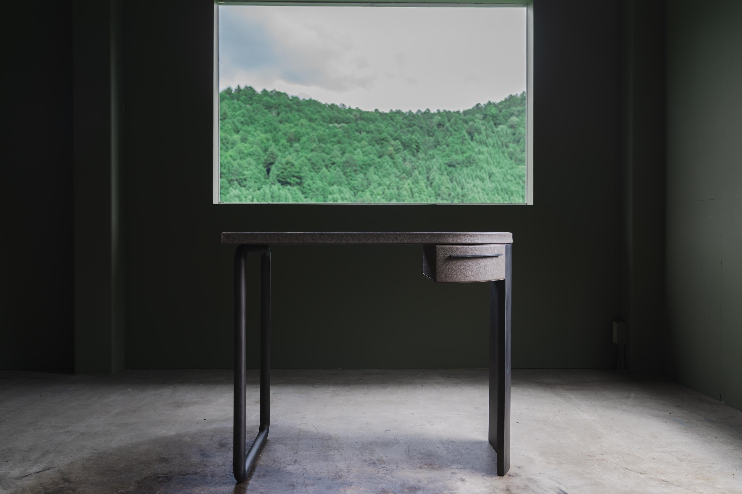 Questa scrivania è stata progettata dal designer giapponese Tadashi Murase e realizzata in uno studio di arredamento italiano. 
Le gambe in ferro sono modellate con tecniche di piegatura e curvatura, rifinite con un rivestimento anticato. Il piano