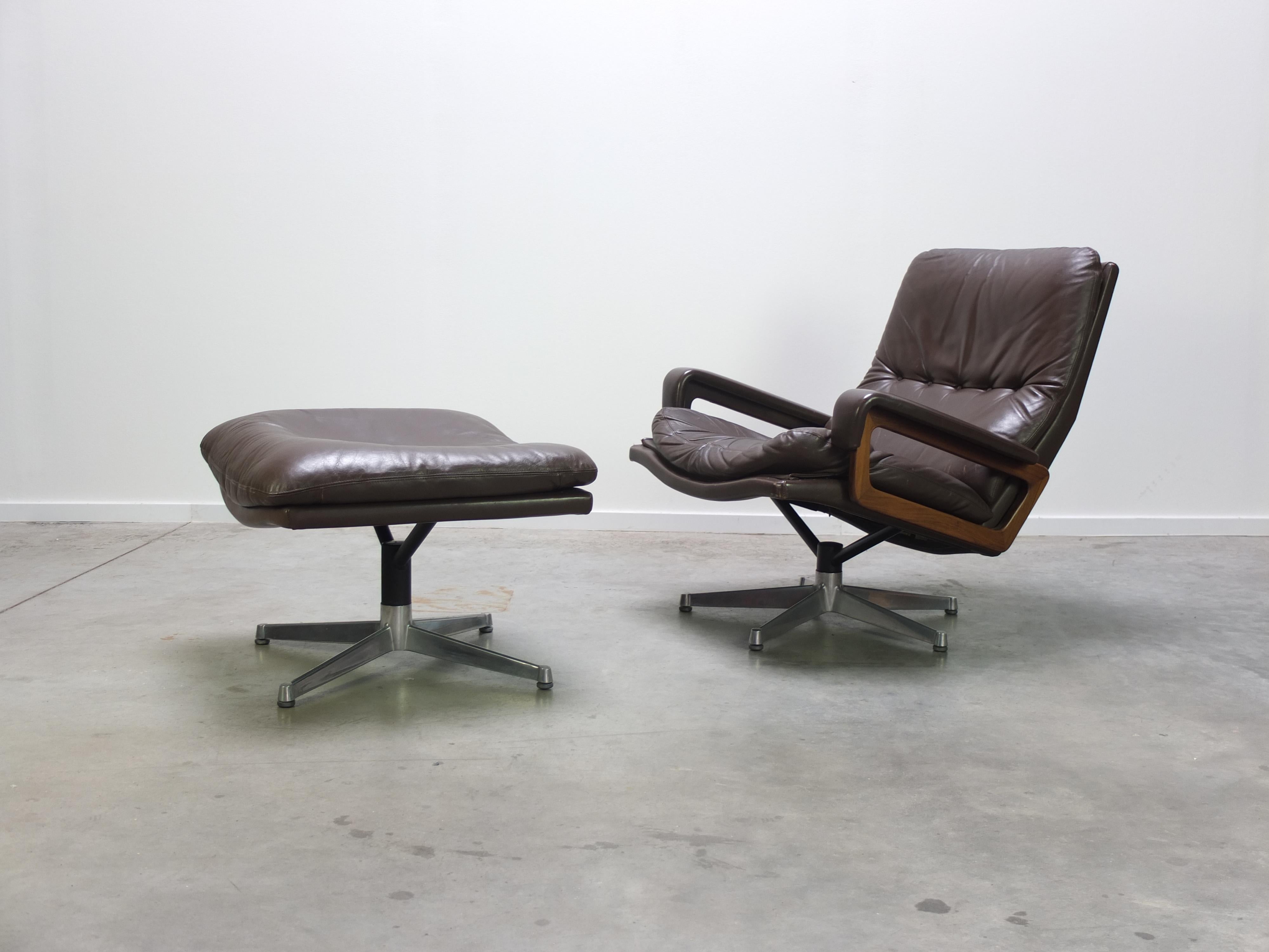 Iconic ‘King’ lounge chair designed by Swiss architect André Vandenbeuck for Strässle during the 1960s. This is a dark brown leather edition with rosewood armrests and the early star-shaped metal base. It also comes with its original matching