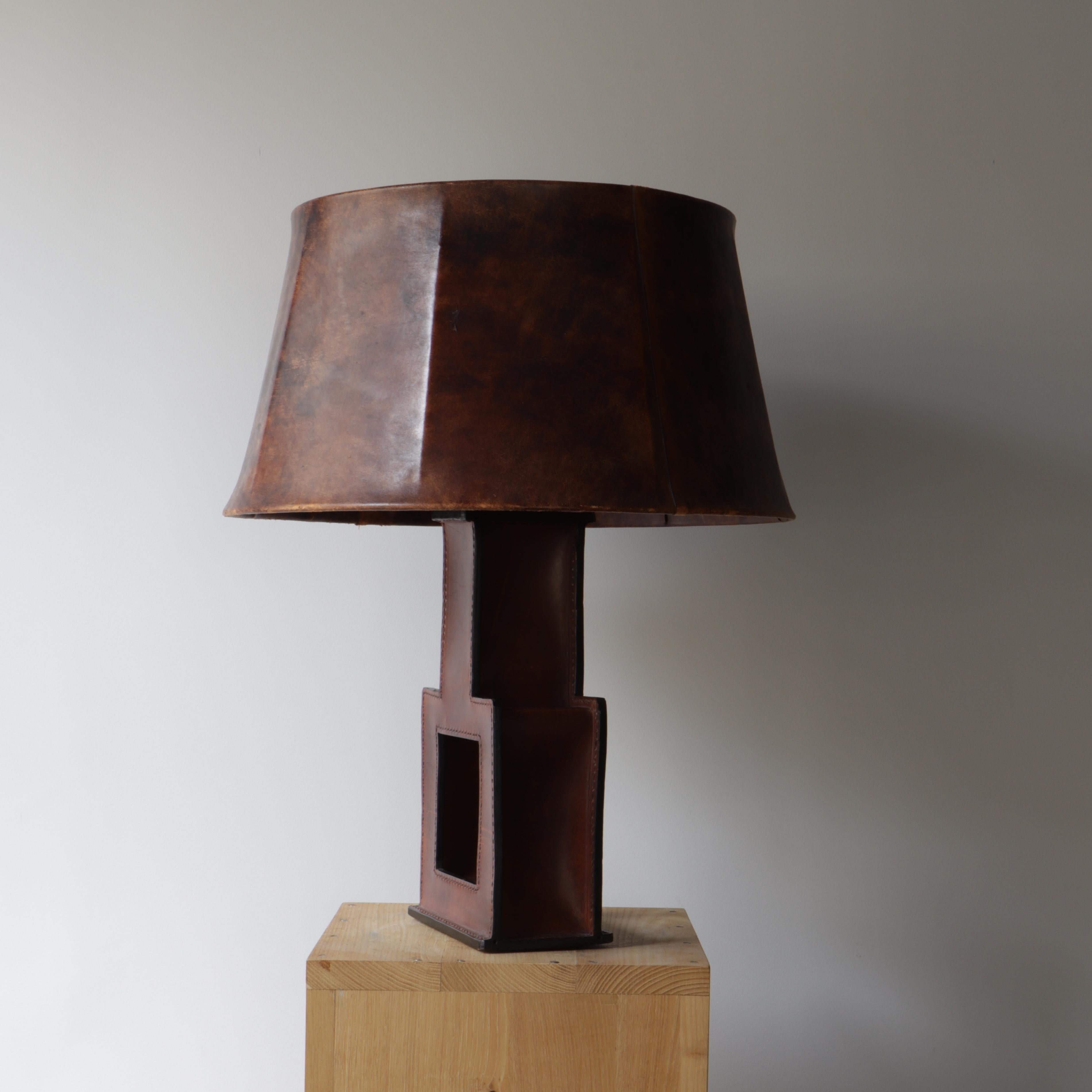 French work dating from the second half of the 20th century. This lamp in the shape of a pierced square carries from the lampshade to the foot its original leather sewn on stitching. It is covered with a nice patina. Presents minor traces of wear.