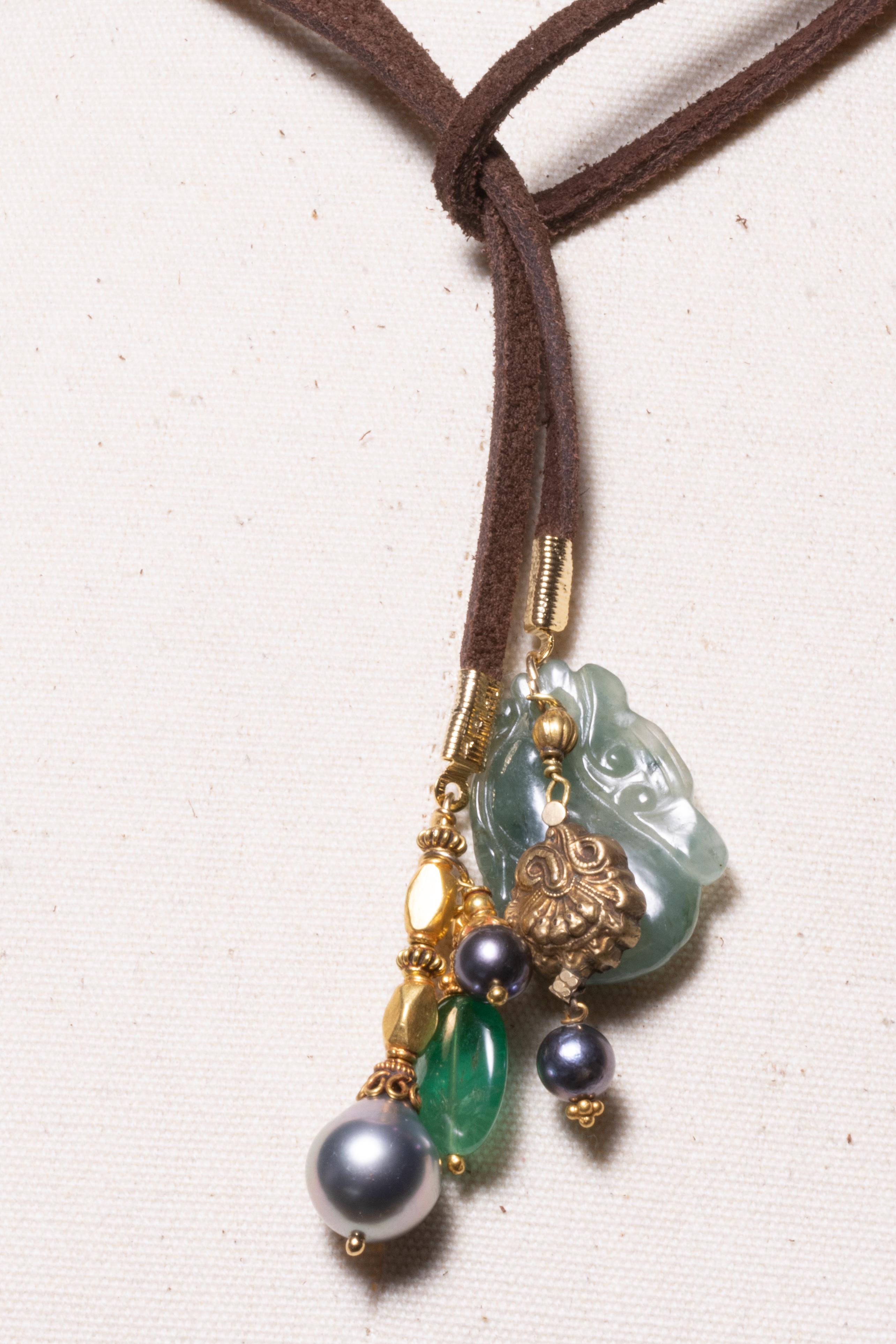 A leather lariat to be worn long or short.  Dangling from each end are 18K gold beads and pendants-- emeralds, gold and jade pendants. Length short is 19.5