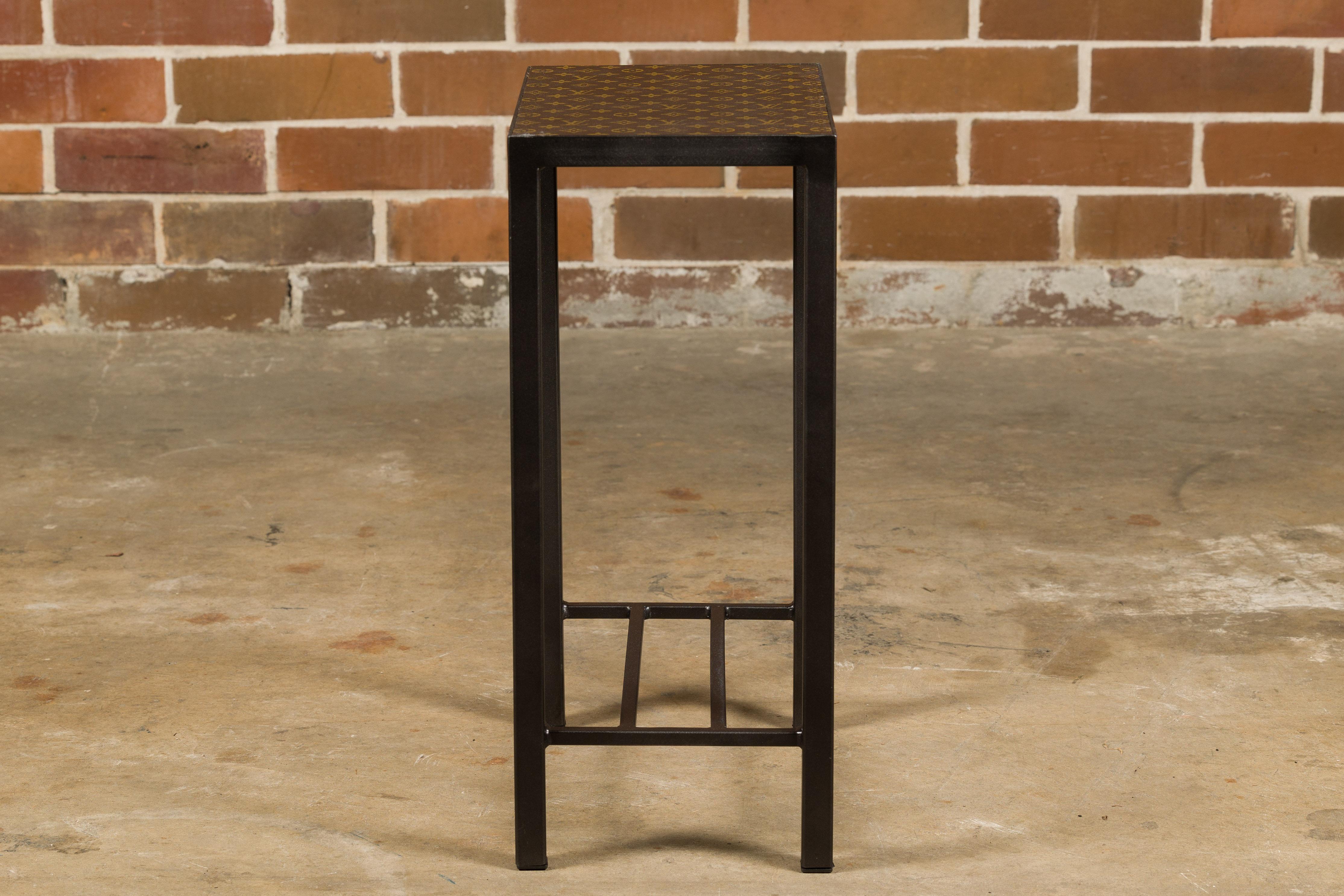 Petite table d'appoint avec un plateau en cuir Louis Vuitton monté sur une base en métal personnalisée avec des traverses. Plongez dans le summum du luxe et de l'artisanat avec cette étonnante petite table d'appoint, dont le plateau est orné du cuir