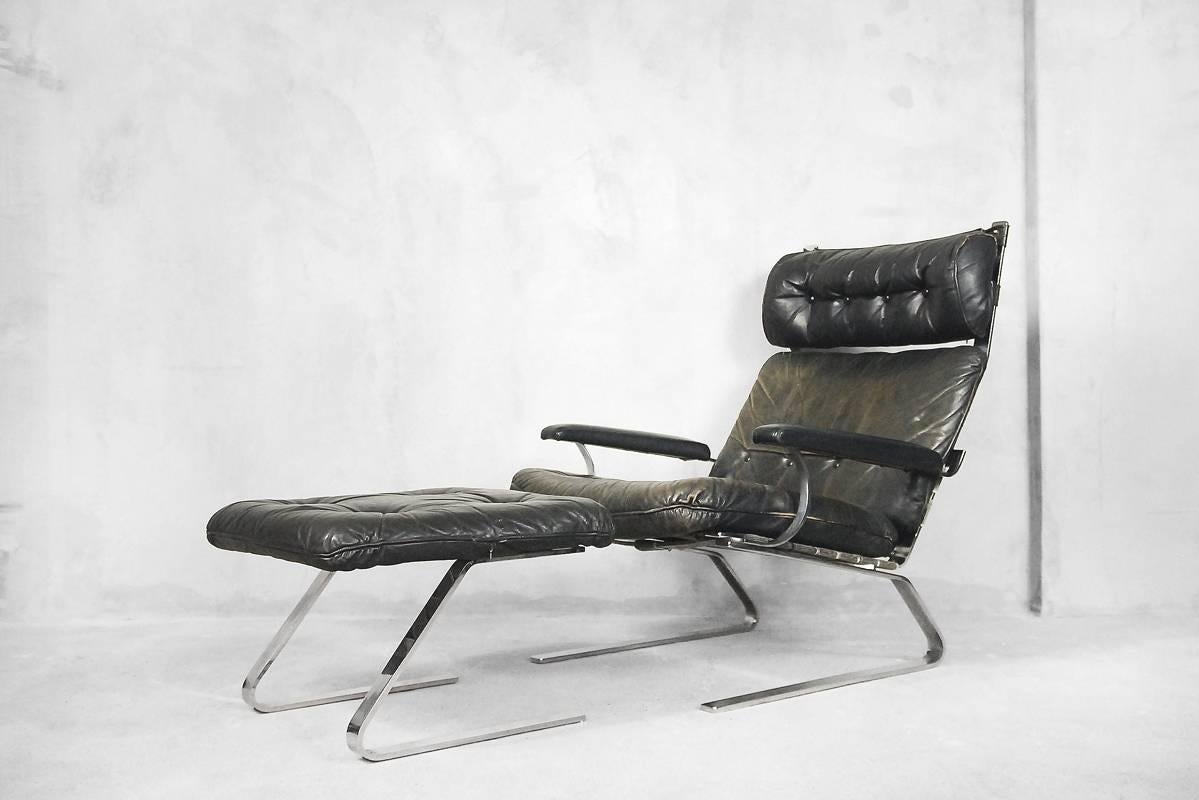 This lounge chair with ottoman was designed by Reinhold Adolf and manufactured by COR during the 1960s. The frame is made of flat steel. The seat and back are made of patinated leather in earthy colors: brown, green and dark gray. The camber frame