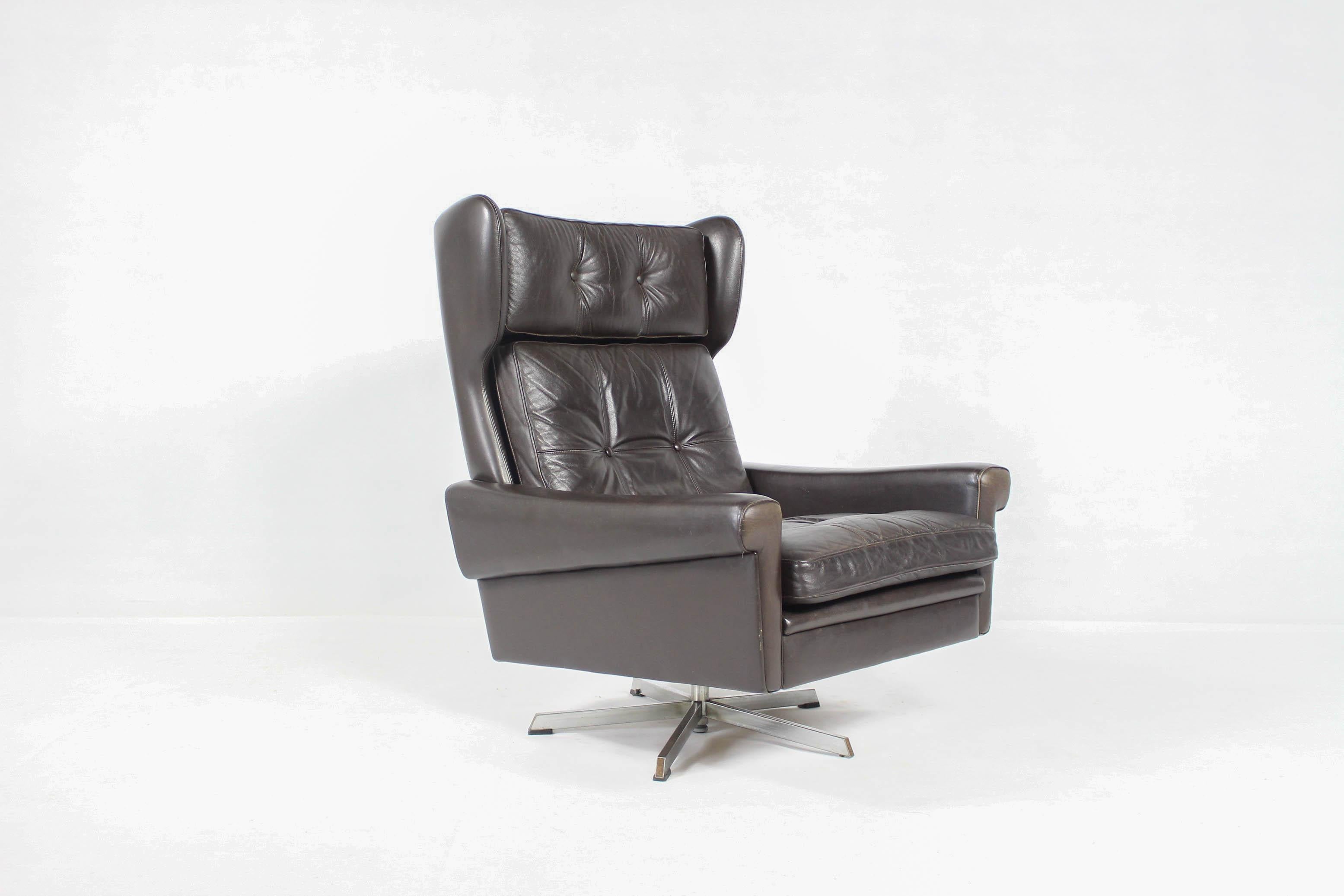 Wonderful high back winged leather lounge chair by Svend Skipper,
with loose cushions upholstered in buttoned dark brown leather.