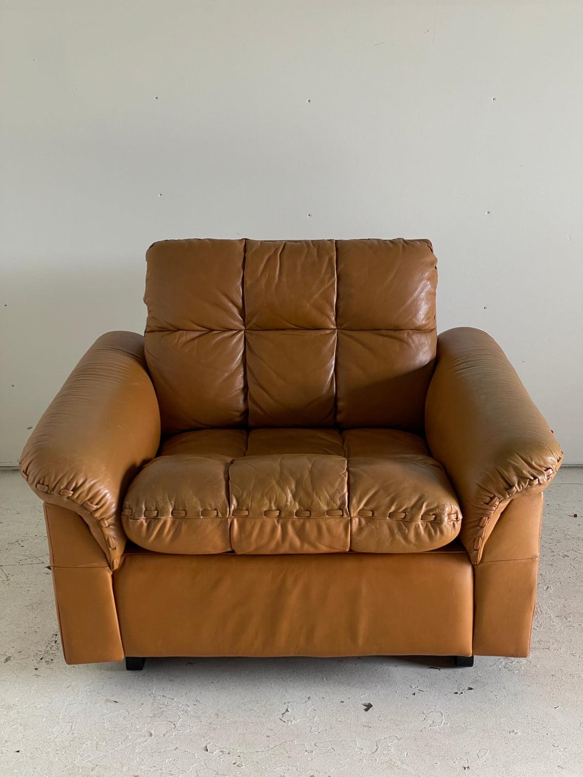 1970s leather lounge chair with incredible patina, woven detailing throughout on a floating wood base with its original tan and white leather checkered pillow. 

36”W x 34”D x 26”H x 17”SH

Pillow 16”L x 12”W x 3”thick.