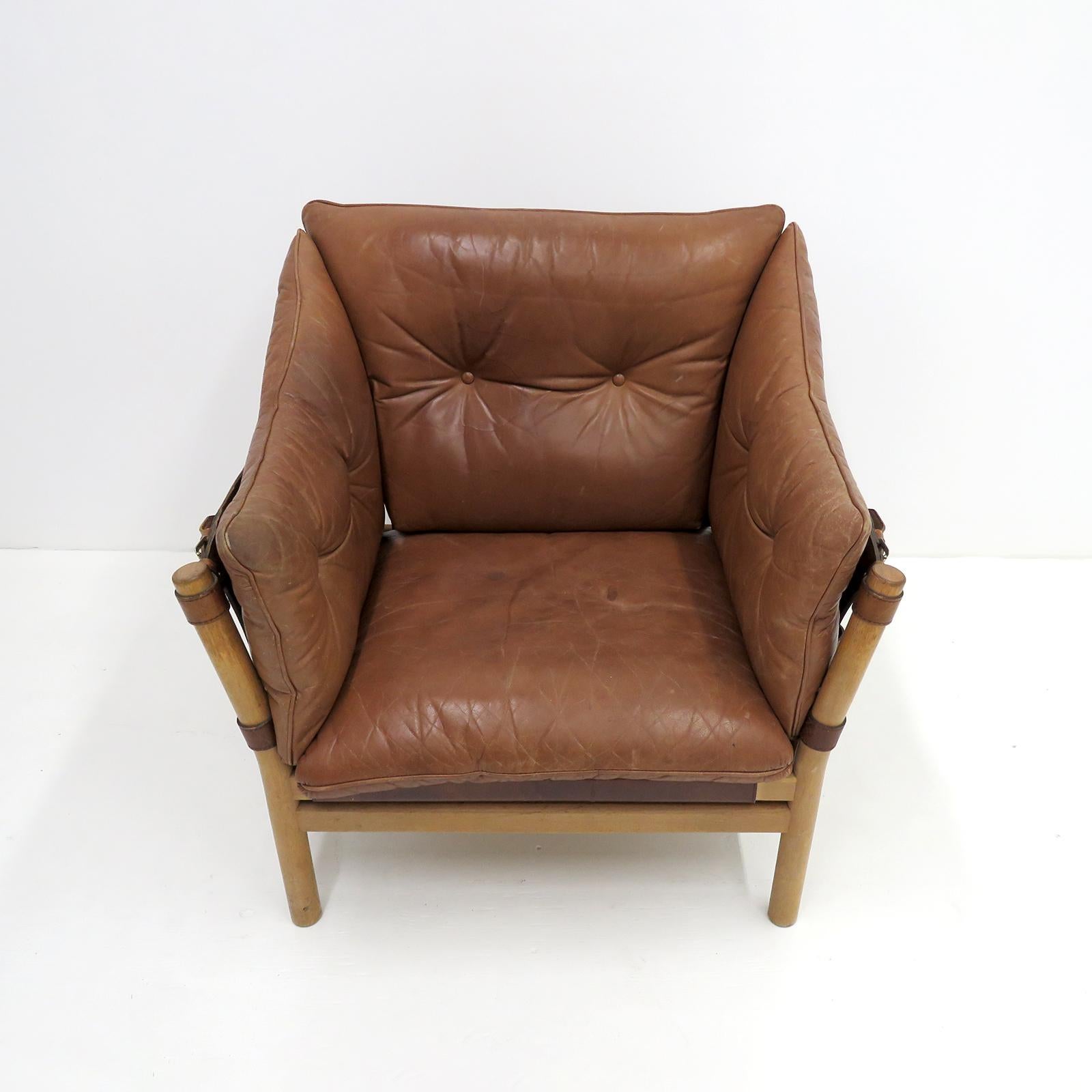 Stunning leather lounge chair designed by Arne Norell in the early 1960s and produced by Aneby Møbler, Sweden, with thick, cognac colored leather cushions on saddle leather sling supports with brass hardware, the frame is made of sturdy, solid,