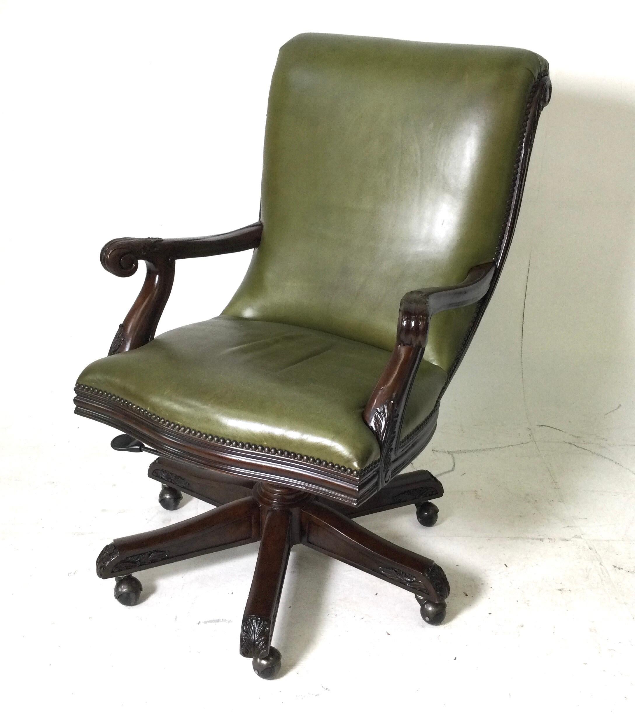 Beautifully carved Maitland Smith desk chair. The wood frame with caved acanthus leaves upholstered in an medium green leather with nail head trim ... The graceful rolled back with hand carved open arms, resting on six leg base with castors.