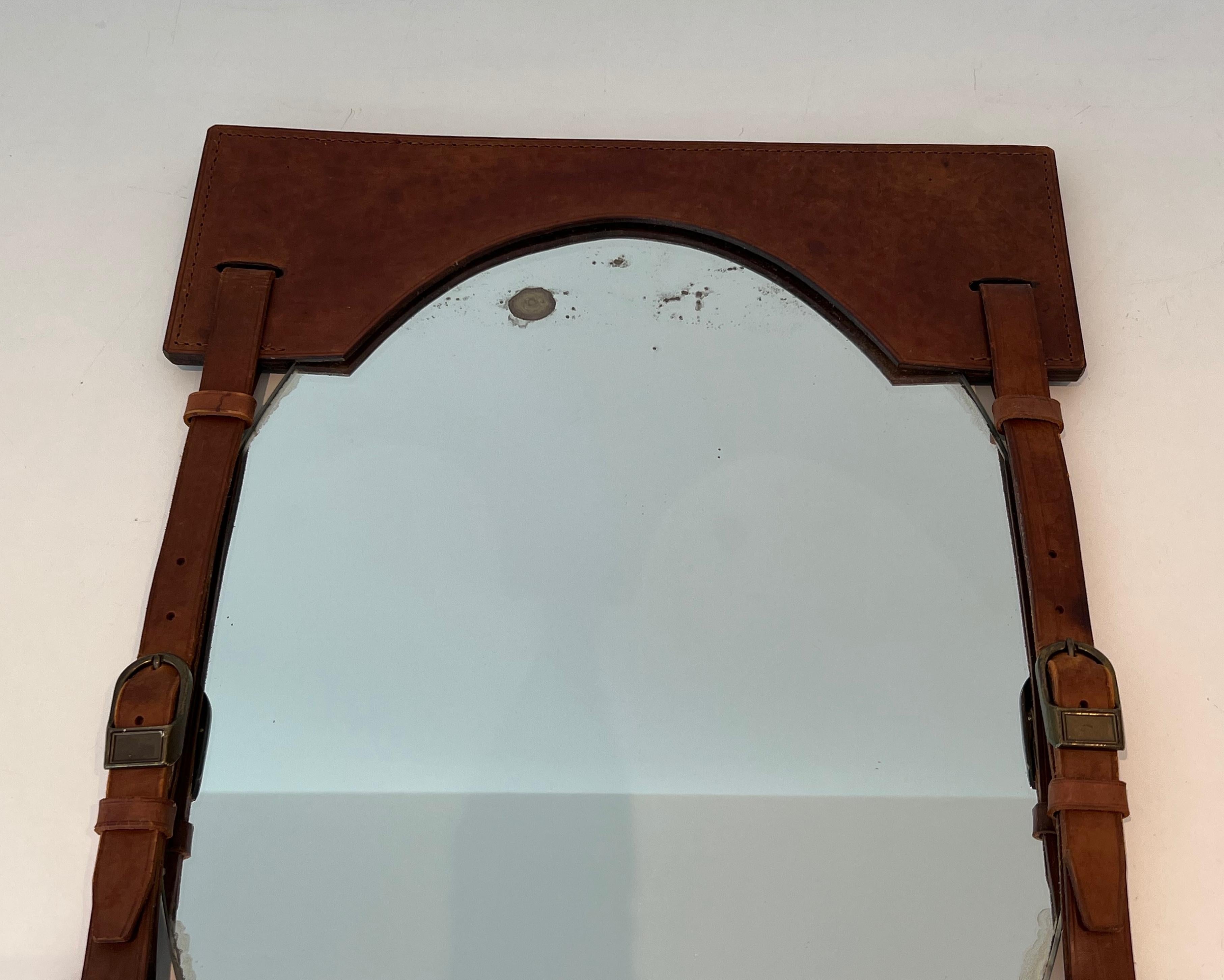 Ce beau et rare miroir est fait d'un beau cuir brun avec des boucles en laiton. Il s'agit d'un ouvrage français dans le style de Jacques Adnet. Circa 1950