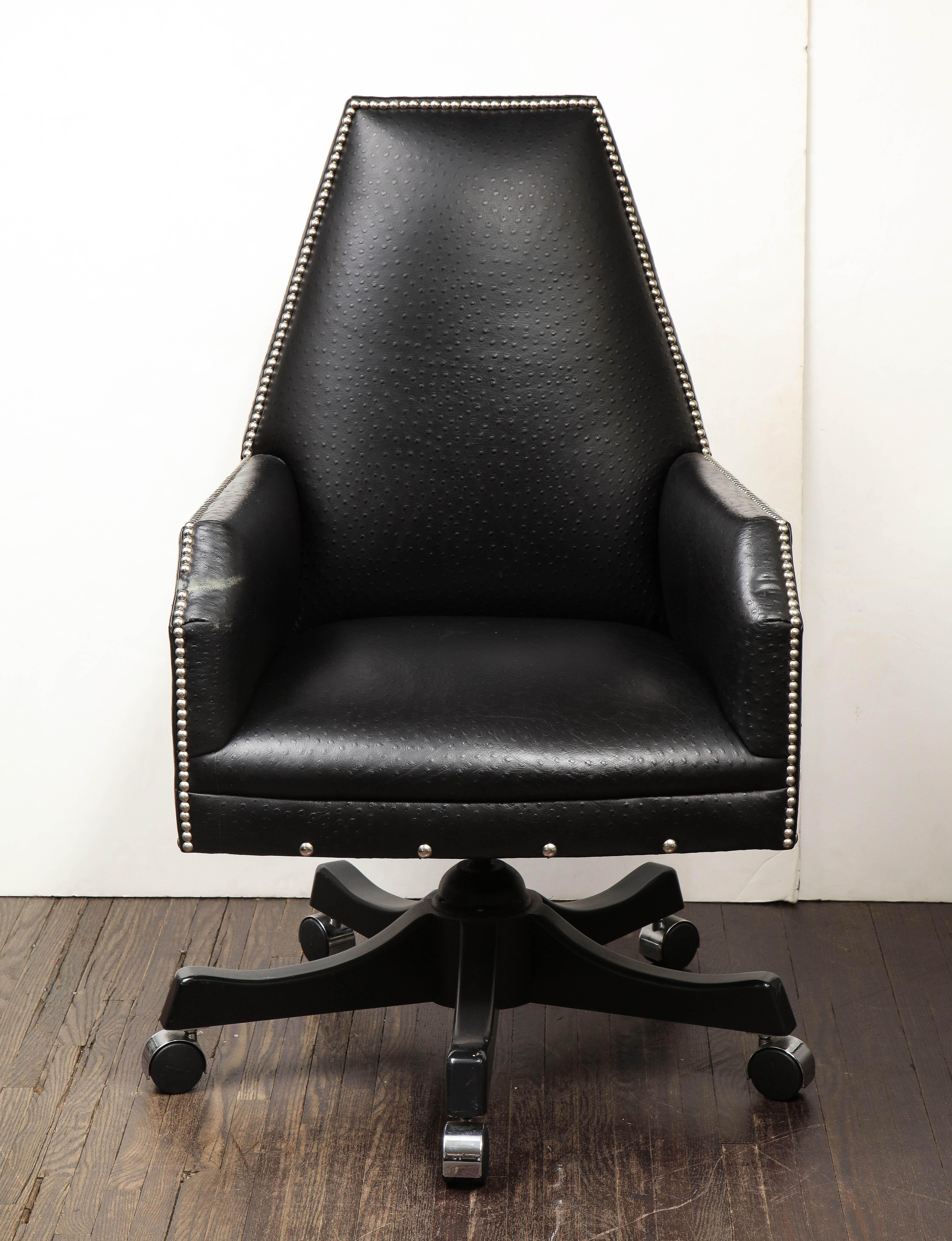 21st century preowned leather desk chair with lacquer swivel roller base and chrome nailheads. The chair is in great shape with some minor wear to the leather on the seat and on the arm. Minor scratching on the lacquered swivel base.