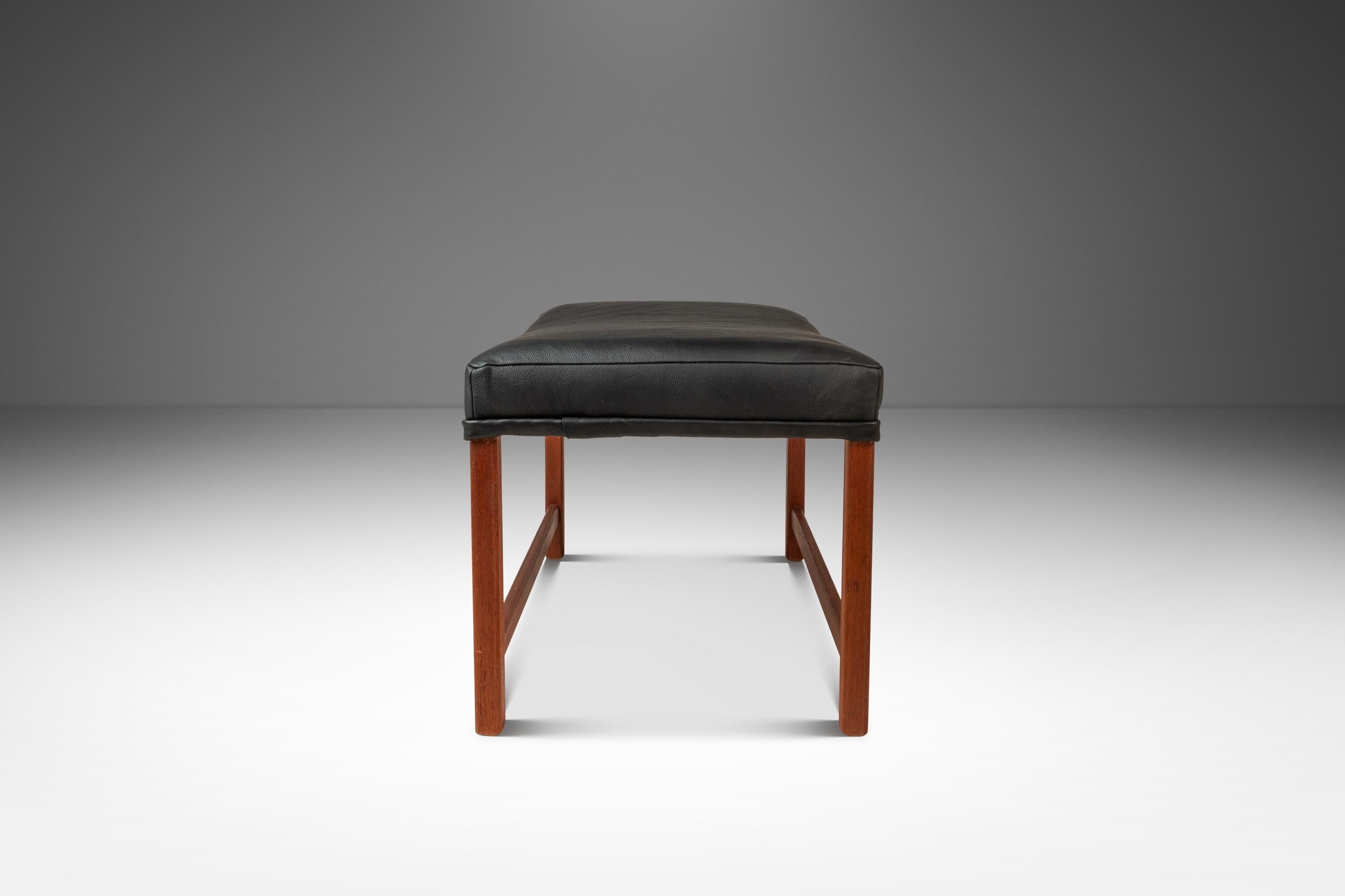  Cet élégant pouf Rio, conçu par Ole Wanscher pour France & Søn, incarne la simplicité raffinée du design scandinave du milieu du siècle grâce à sa construction en teck massif. Nouvellement revêtu d'un luxueux cuir noir Ebony, l'ottoman offre un