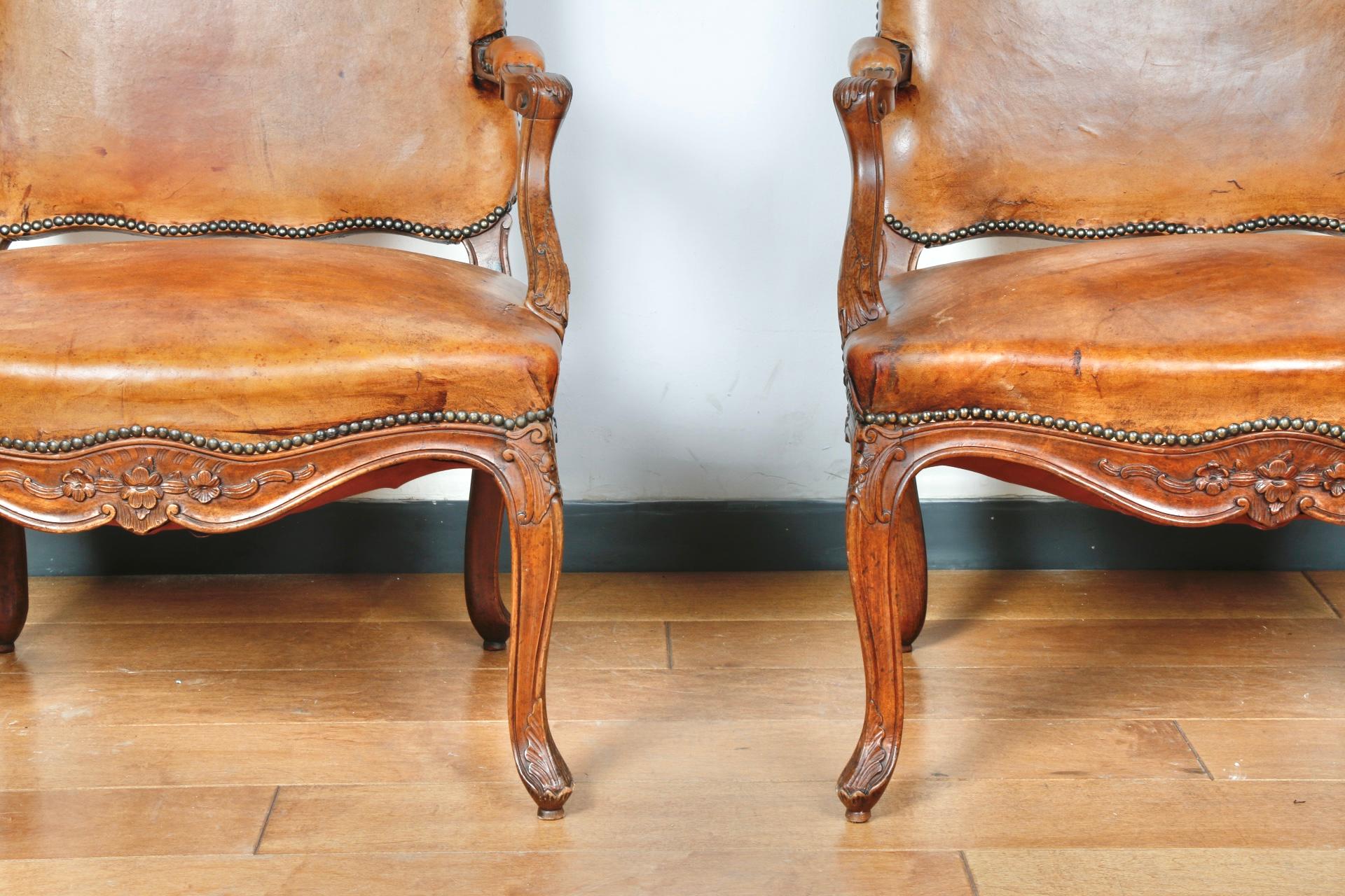 Superbe paire de fauteuils Bergère en cuir avec de beaux détails en bois sculpté sur la base. Très solide et robuste, sans pièces cassées.