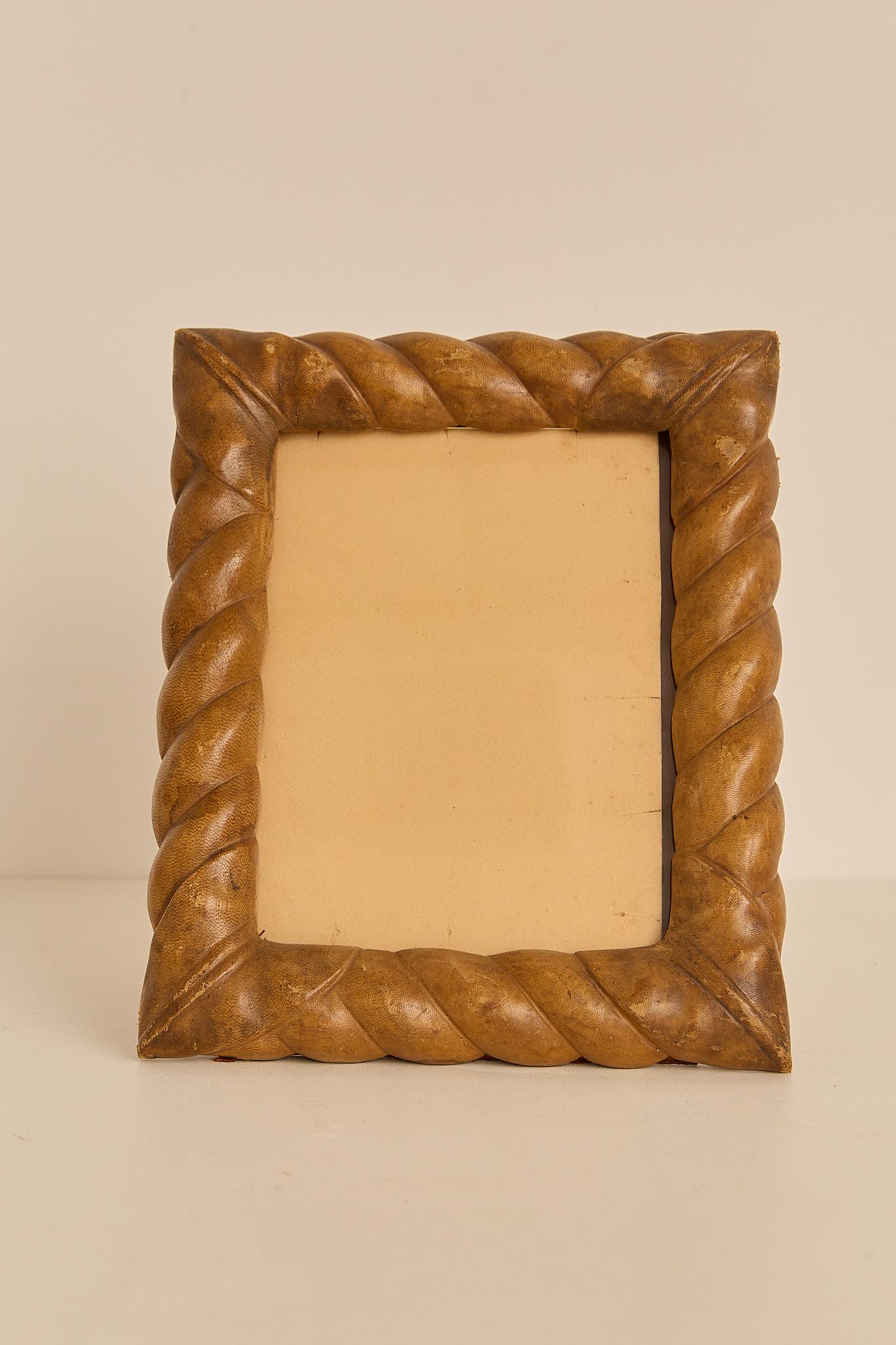 Cadre photo italien fabriqué à la main dans les années 1970, enveloppé dans un cuir richement patiné. La bordure épaisse et torsadée ajoute une texture sculpturale et de la chaleur, mettant en évidence une usure subtile qui rehausse son caractère