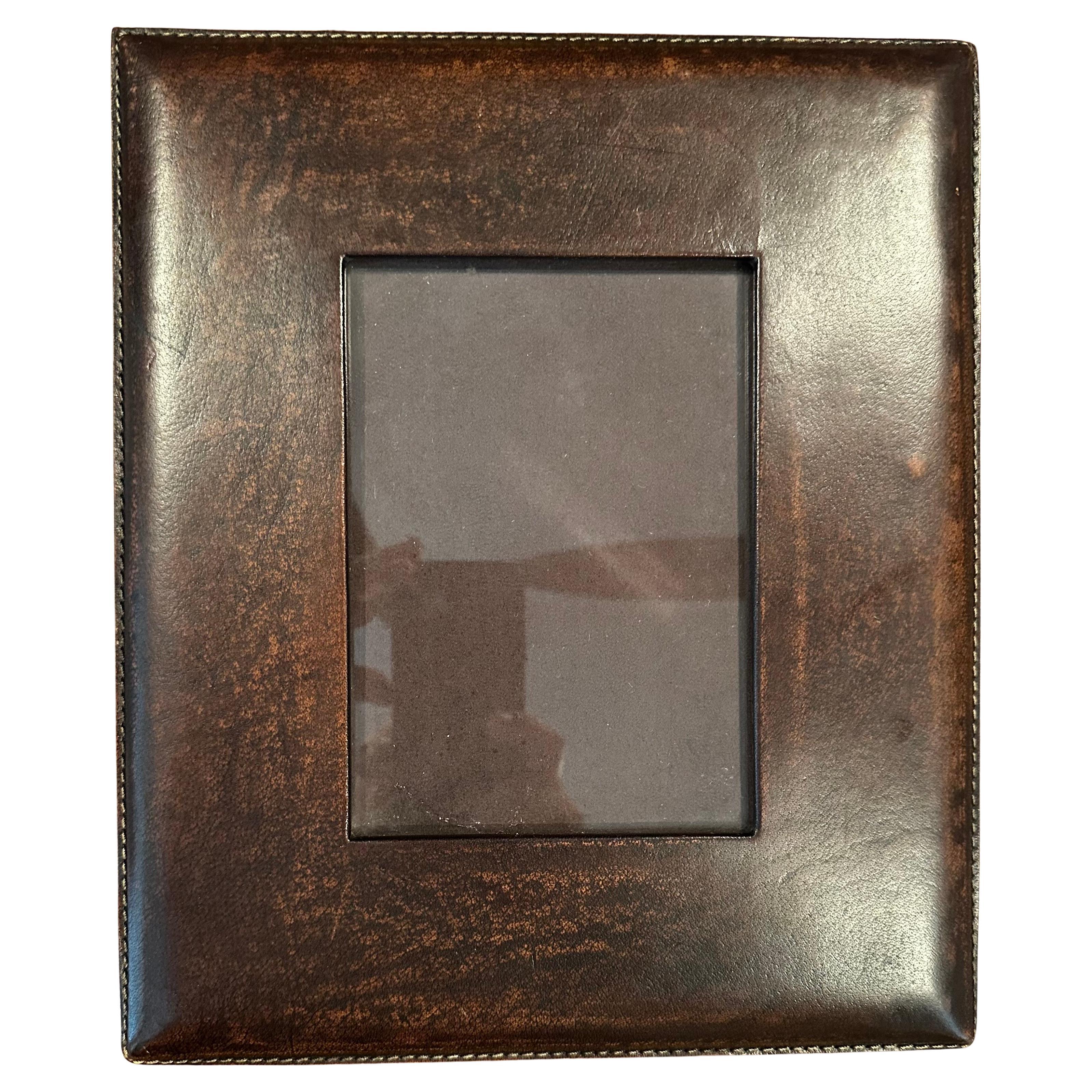 A beautiful hand crafted brown leather picture frame in the style of Ralph Lauren, circa 2000s.  The frame holds a 5