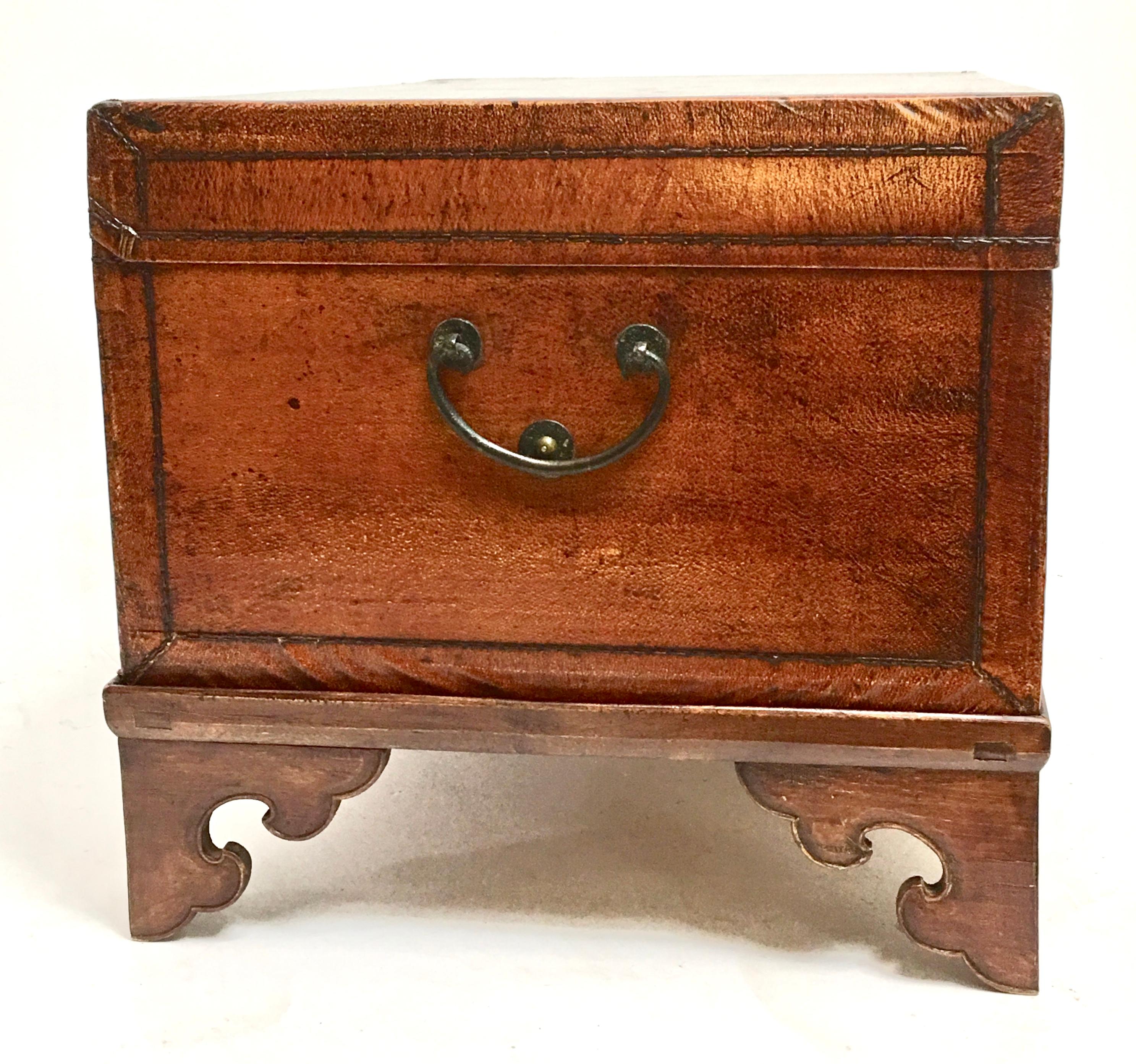 Leather pig skin trunk on custom later stand. The trunk was originally used for storing ceremonial robes interior is paper lined, the exterior with a warm cognac color finish with brass handles and interesting locking latch, the trunks sits on a