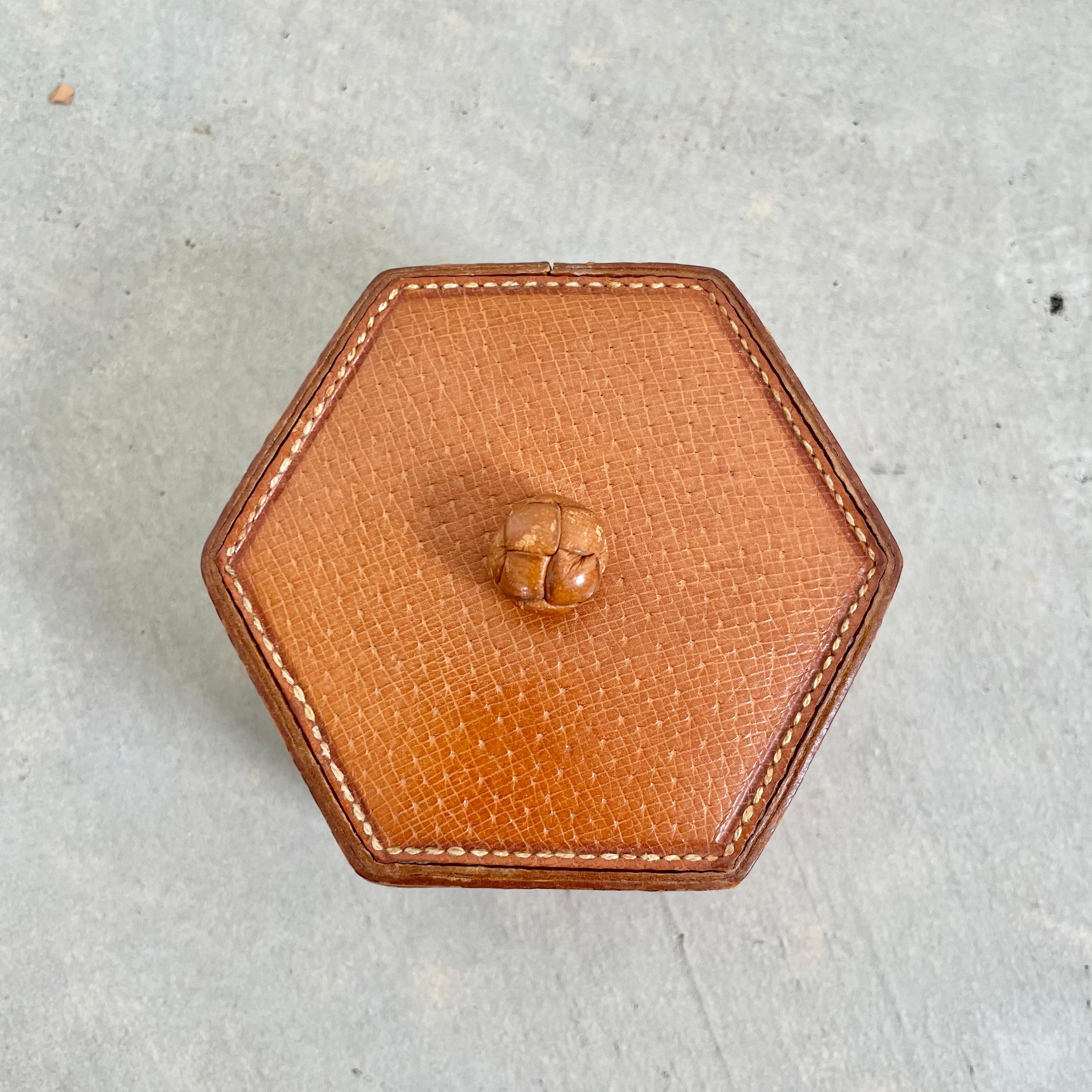 Leather French box in a small size perfect for storing jewelry and other trinkets. Made of beautiful tan saddle leather in great condition with a woven leather ball attached to the top as decoration and also to open the box. Great for a desk or
