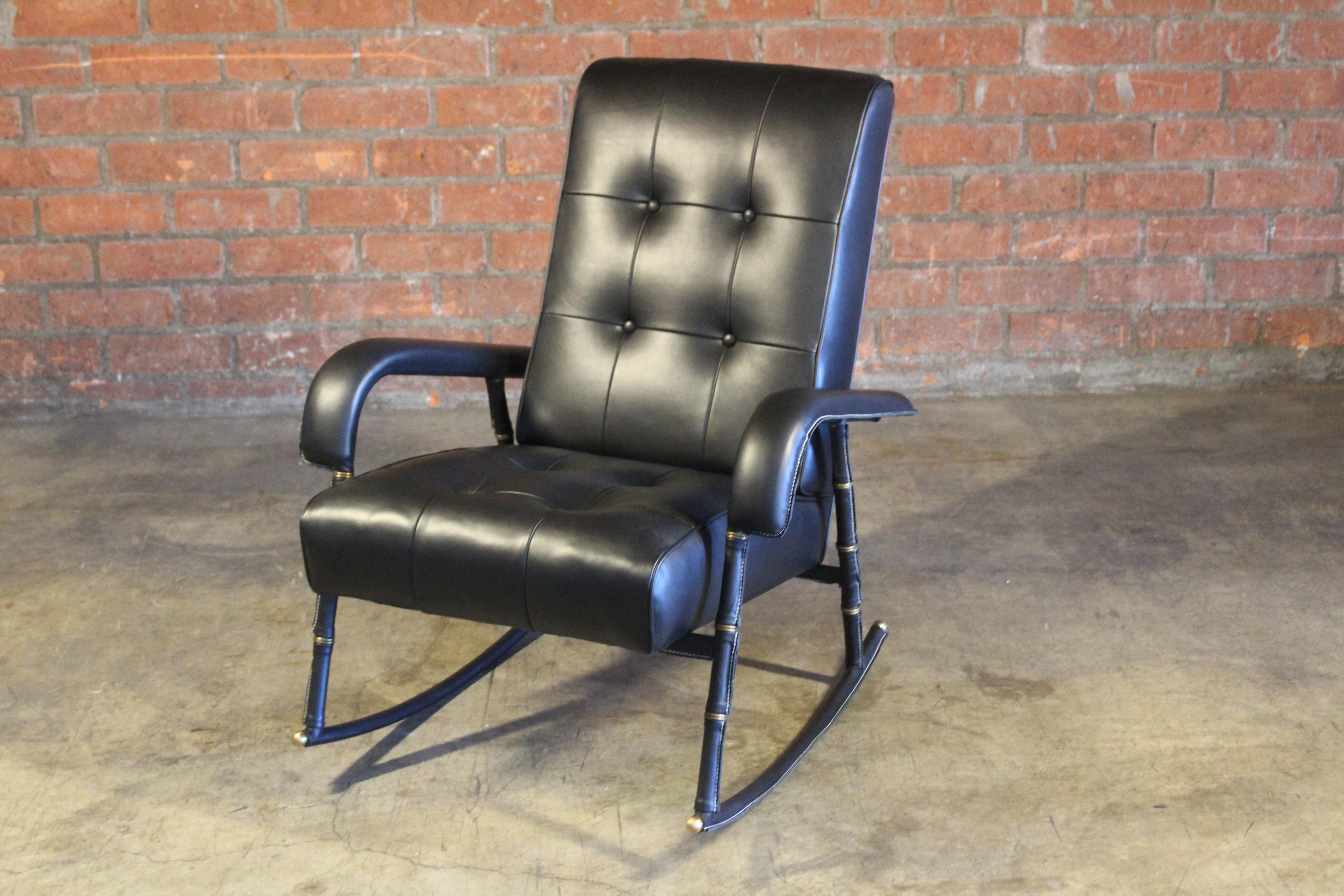 A vintage leather and brass rocking chair designed by Jacques Adnet, France, 1950s. Newly upholstered in genuine black leather. In excellent condition with minor patina to the brass accents.