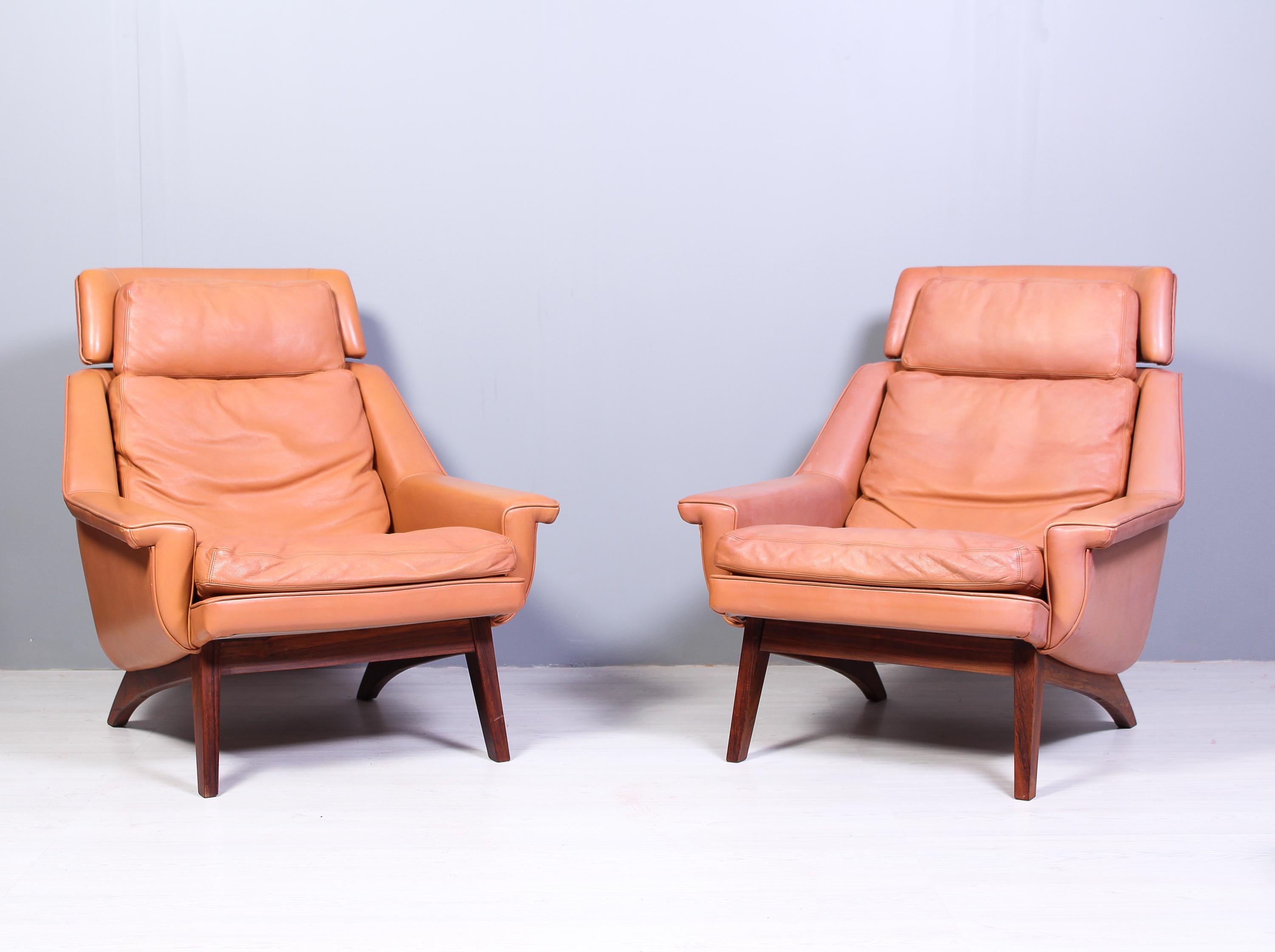 A pair of midcentury lounge chairs and an ottoman designed by Werner Langenfeld and produced by ESA in Denmark in the 1960s. The chairs and ottoman have a nice cognac colored leather upholstery and rosewood frames. This model with the rosewood frame