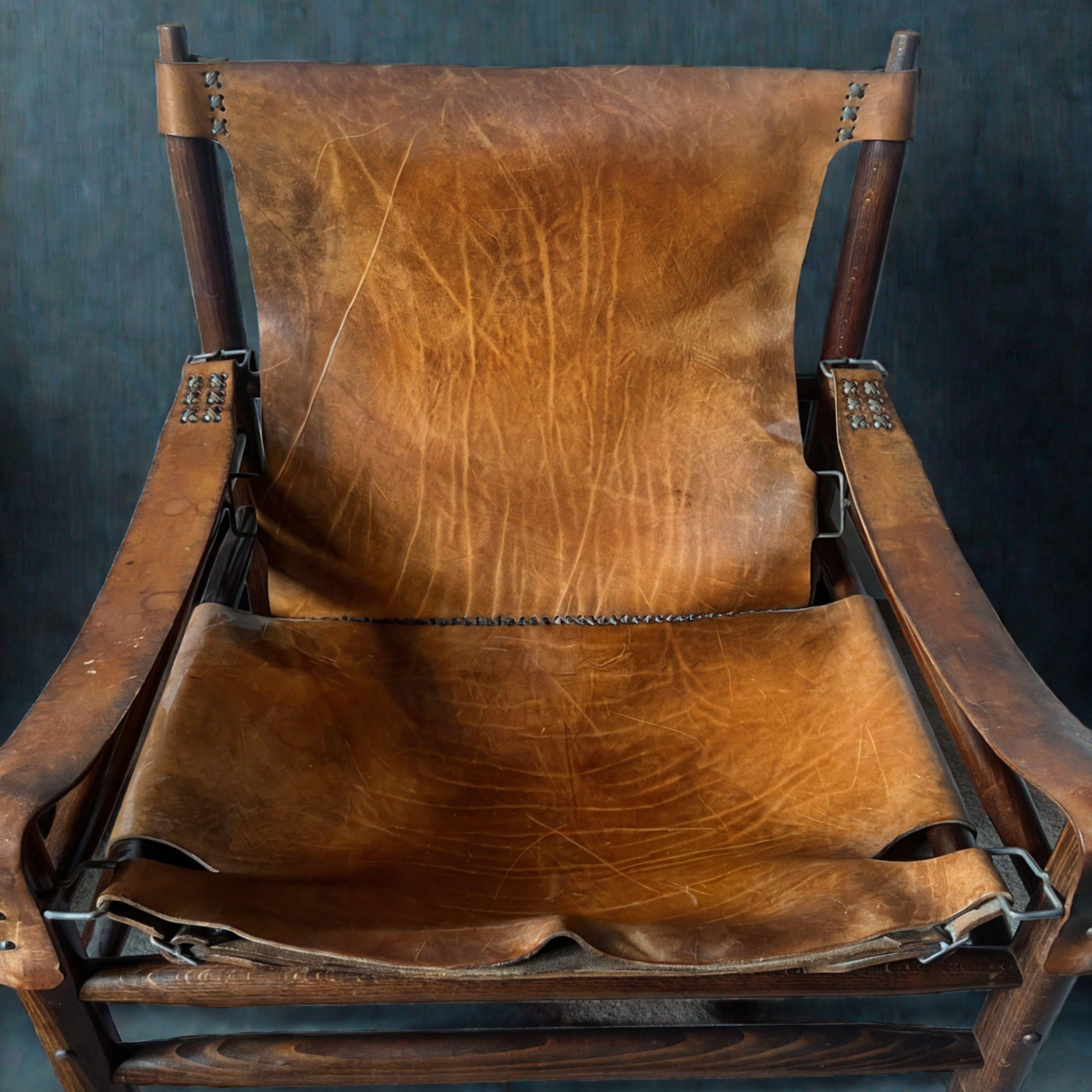 Safari chair with ottoman made of leather with a beautiful patina. Manufactured in the 1970s. Thanks to the solid wood and unique joints, their structure is extremely stable.