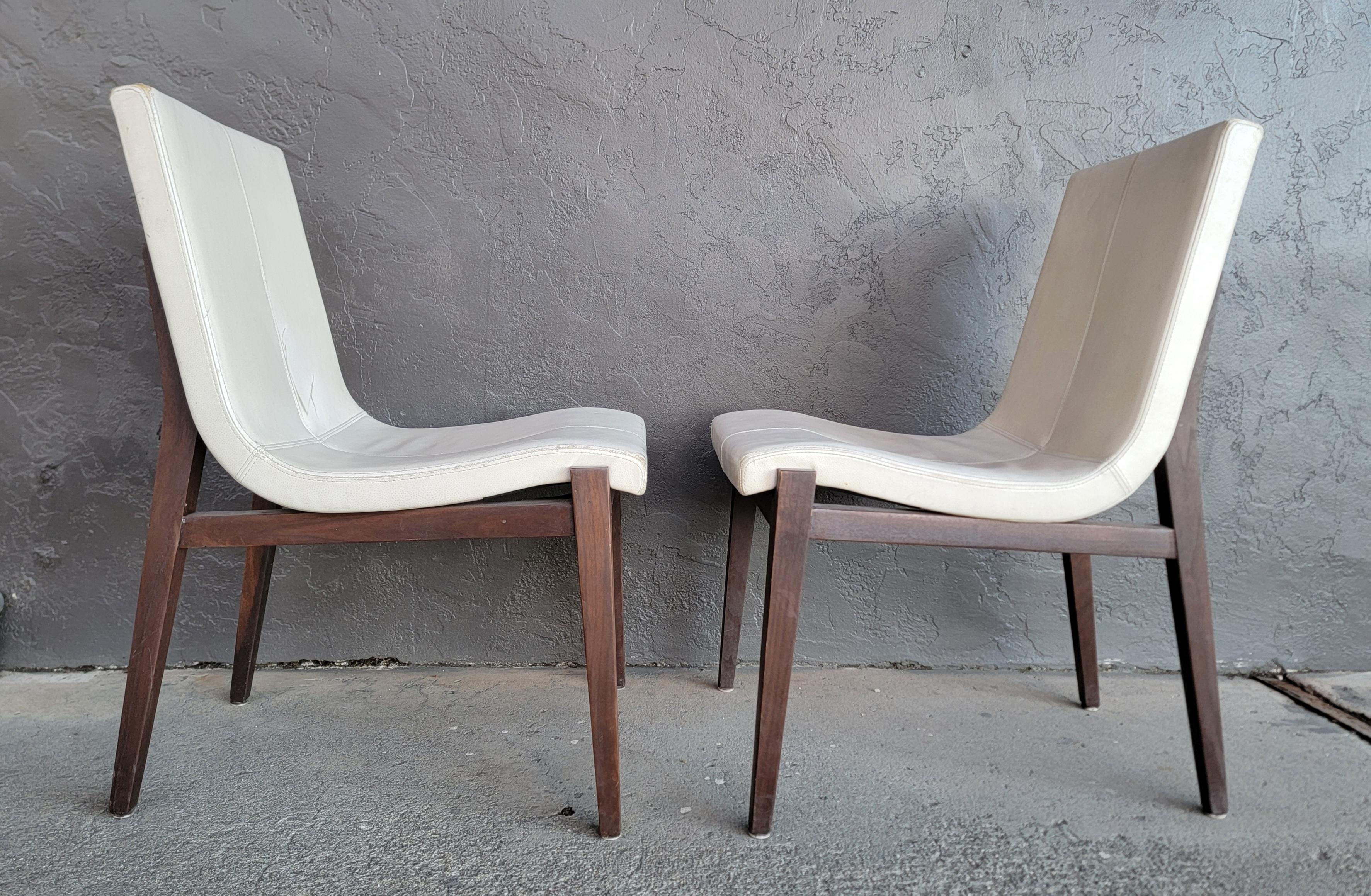 A pair of leather scoop dining chairs by Holly Hunt. Retaining metal label 