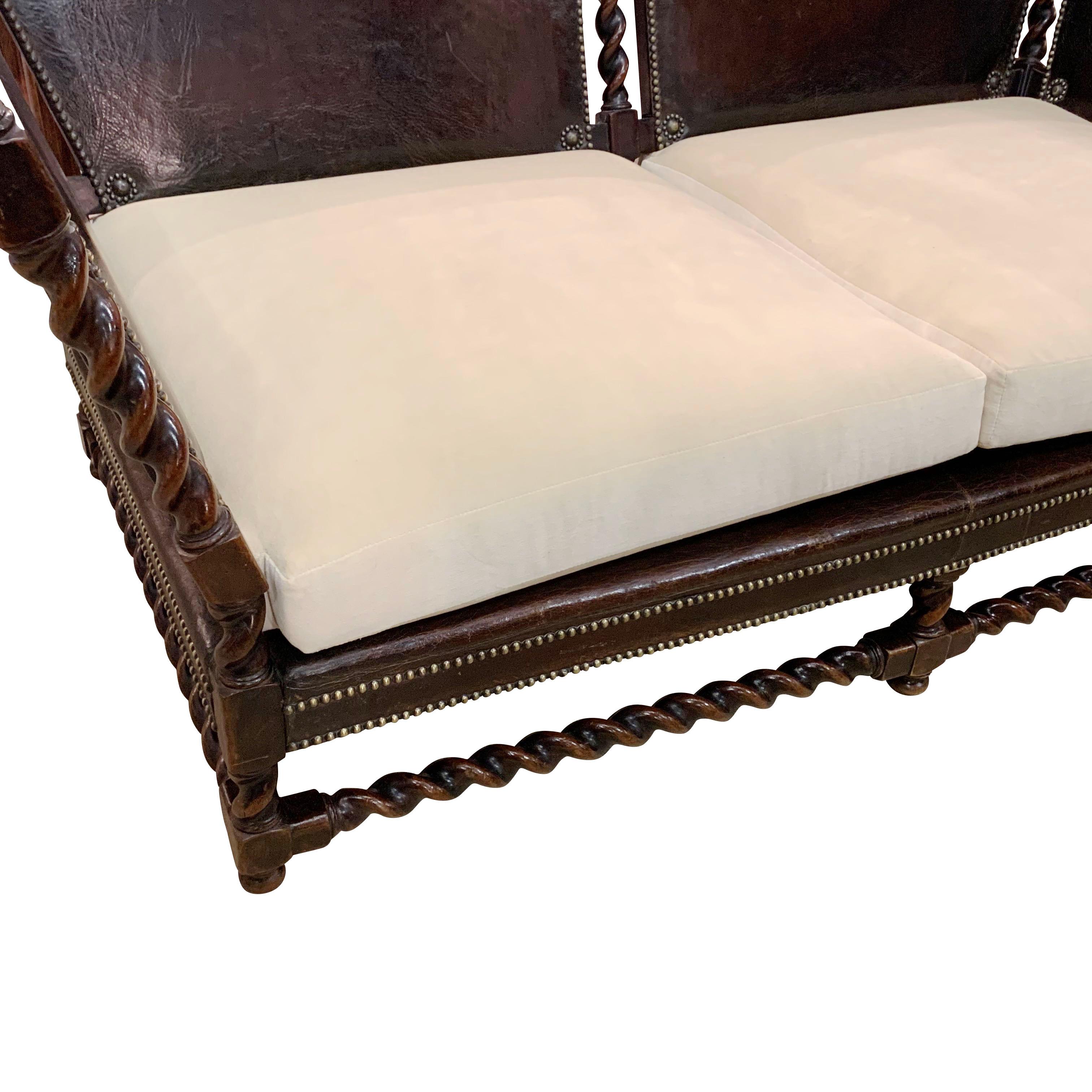 1890 French leather with brass stud detailing setee
Angled side arms
Spindle legs and arms
New seat and back cushions.
  
