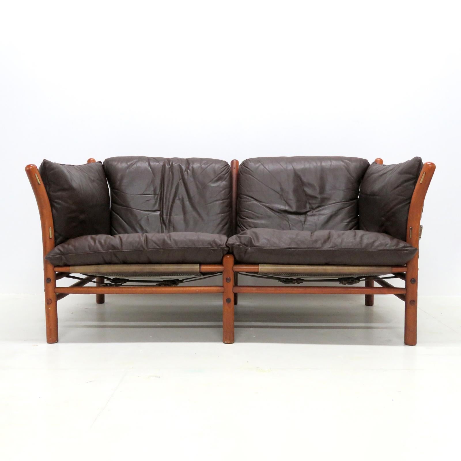 wonderful leather settee designed by Arne Norell in the early 1960s and produced by Aneby Møbler, Sweden, with thick, dark leather cushions on saddle leather sling supports with brass hardware, the frame is made of sturdy, solid, dark stained beech,