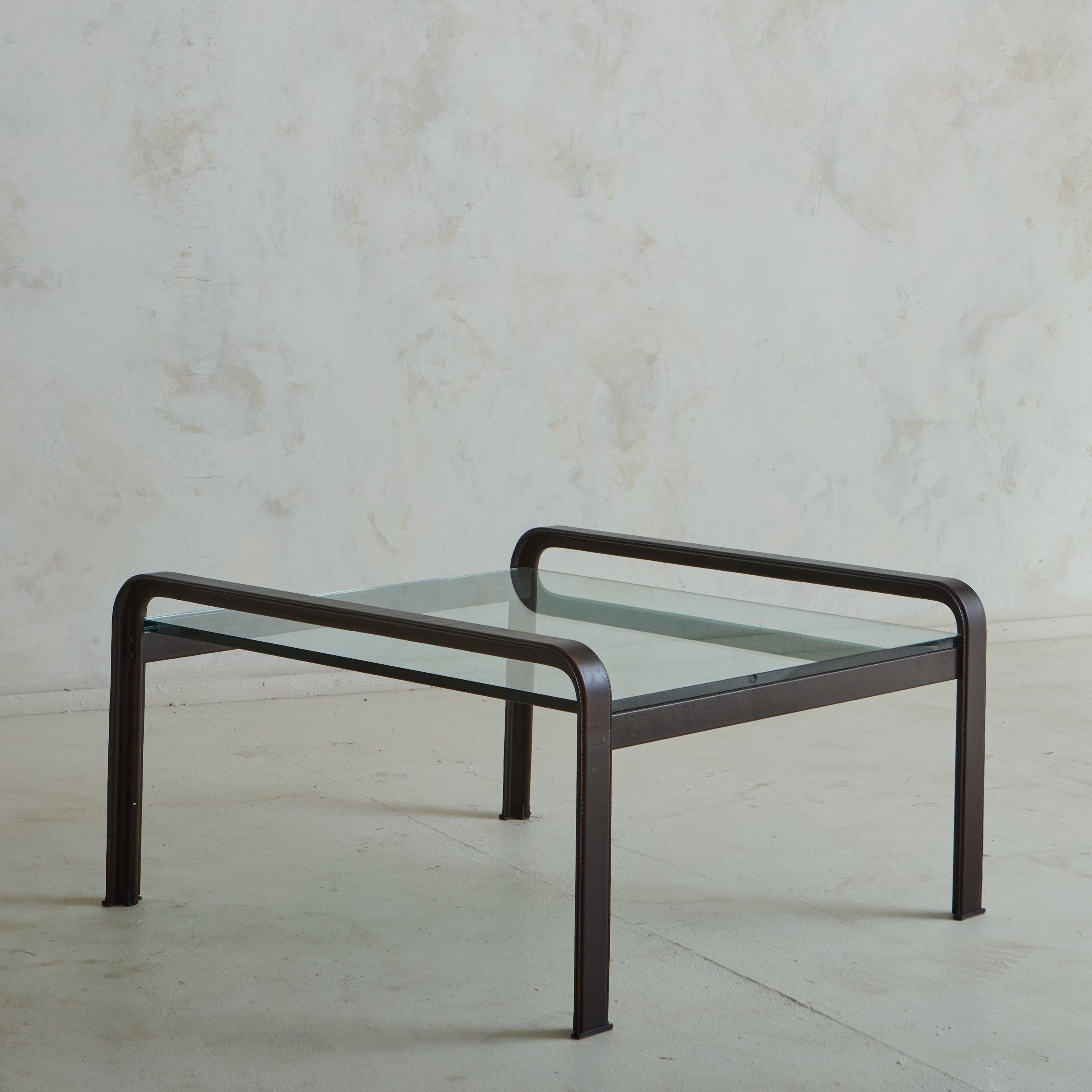 A Mid Century Italian side table designed by Tito Agnoli for Matteo Grassi in the 1970s. This classic table features a steel frame clad in chocolate brown leather with stitch detailing. The sides of the frame curve elegantly above the thick inset