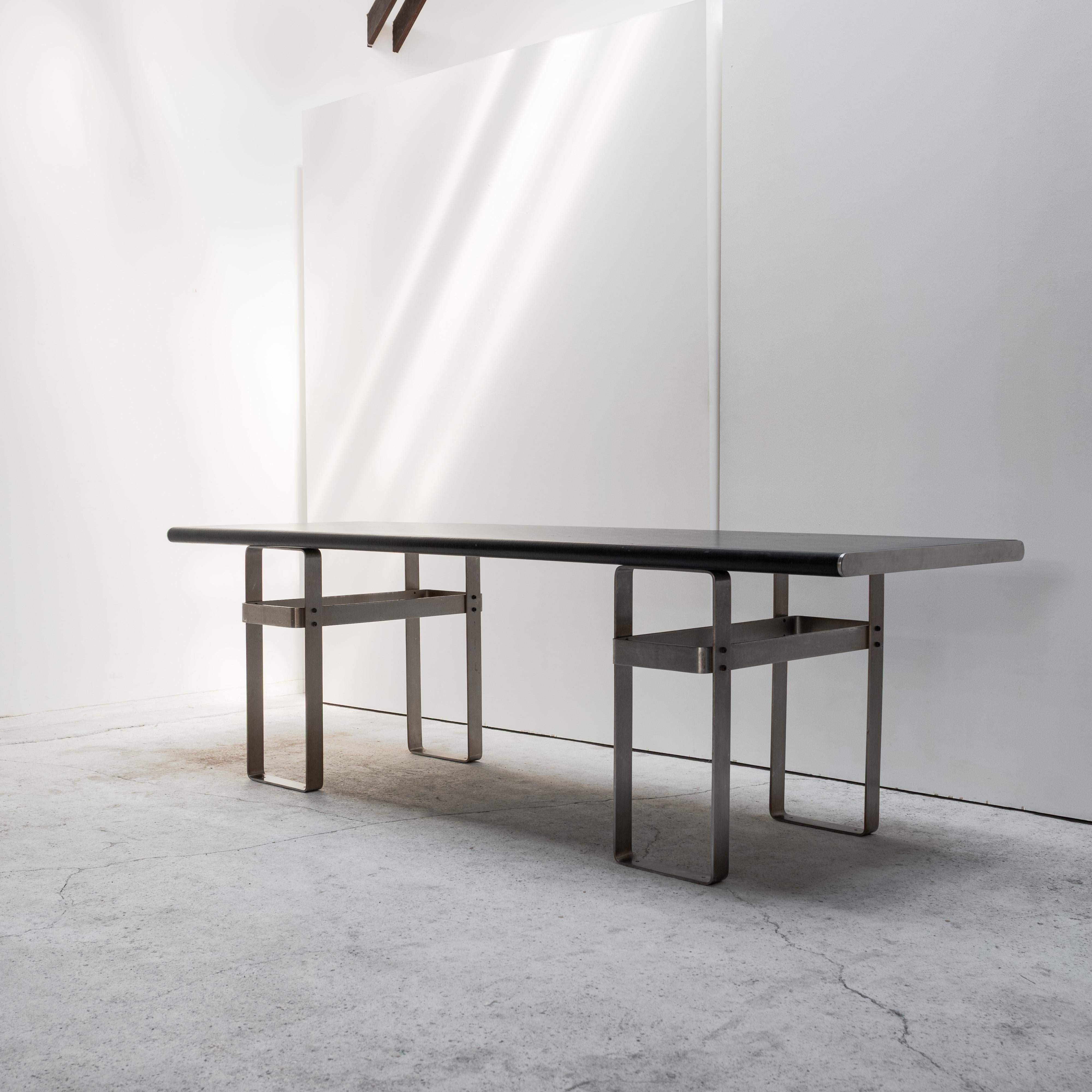 Una mesa única y visualmente impactante producida como parte de la colección Gavina.
Esta pieza presenta una parte superior envuelta en cuero negro mate y una base geométrica de acero inoxidable: una audaz interacción de suavidad táctil y claridad