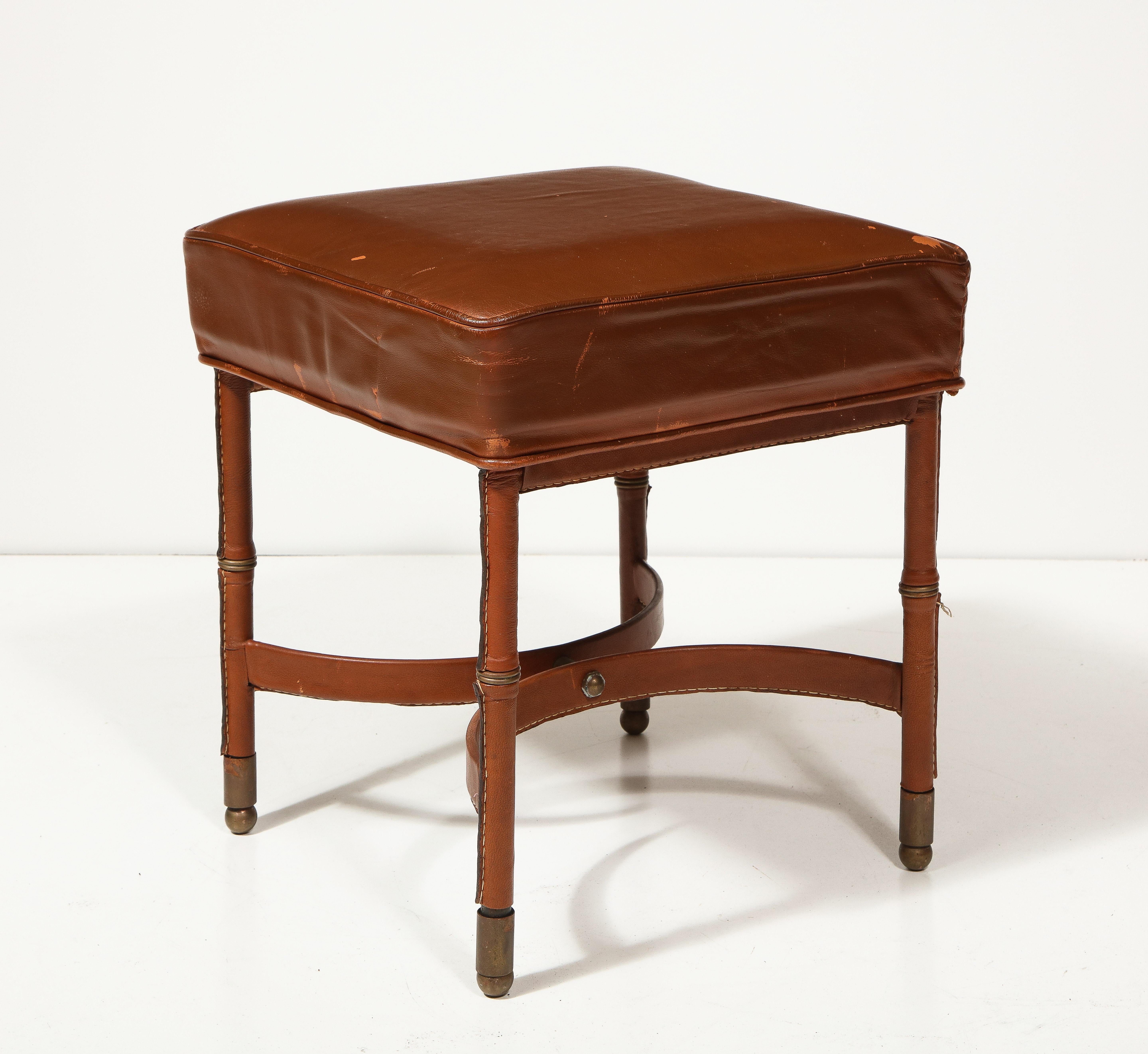 Gorgeous leather stool with stitched leather legs and patinated brass capped feet. This is a great example of Adnet's work; a real collector's item.
