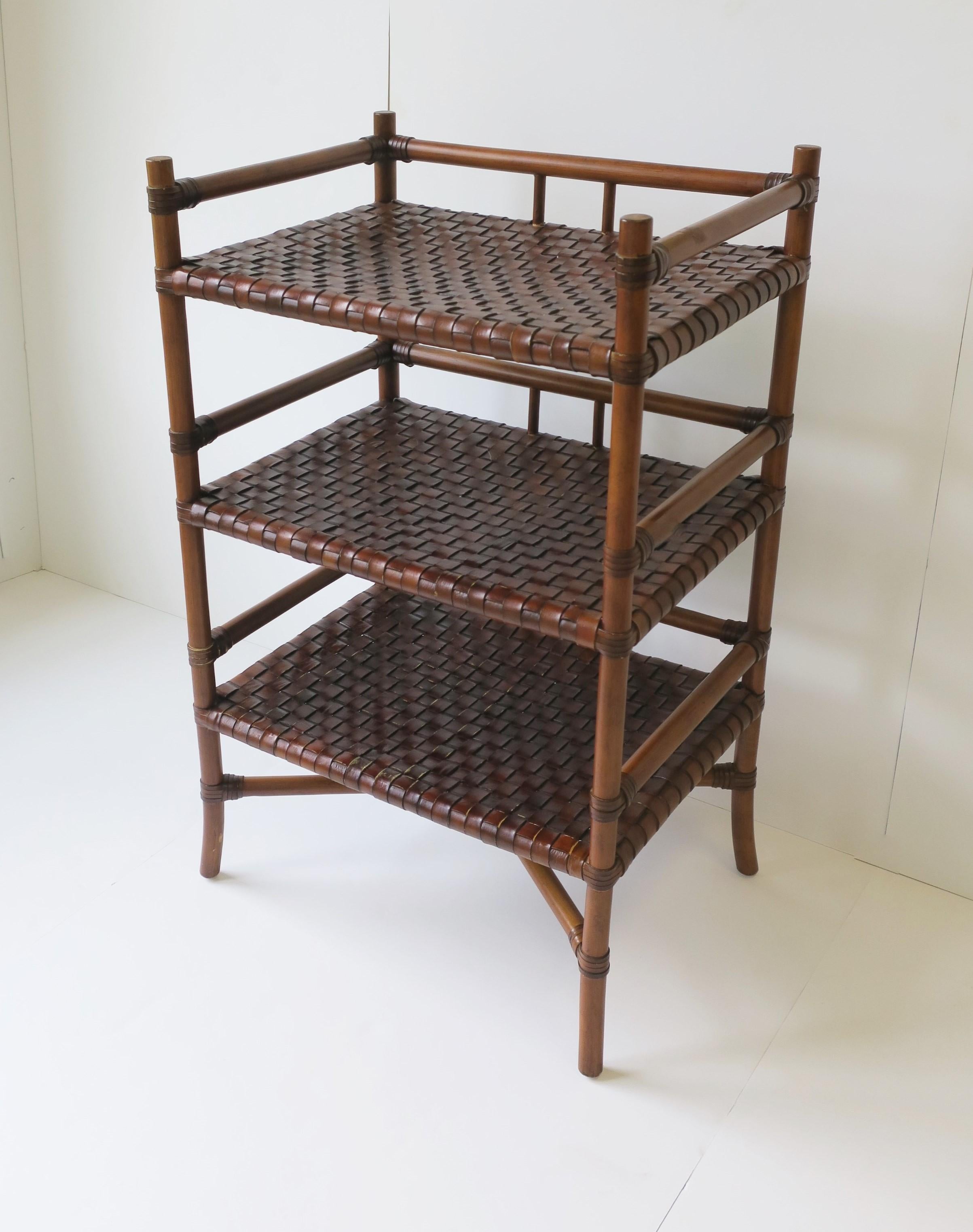 A three (3) tier rich brown storage Étagère, rack or stand, with weaved leather shelves, circa late-20th century. Étagère/storage stand has a rattan-style frame with three (3) shelves made of brown woven leather, wrapped leather detail on frame, and