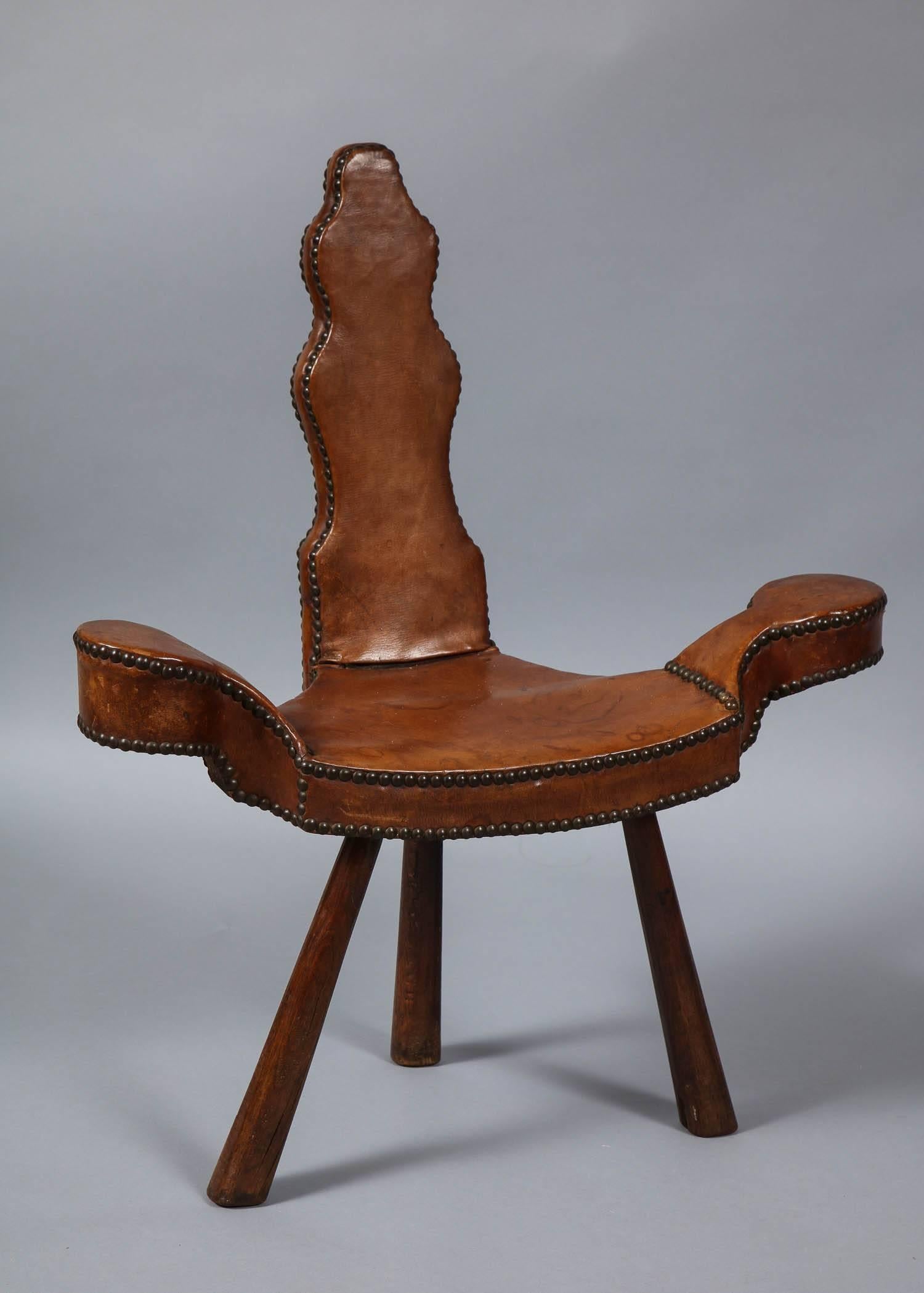 A diminutive armchair with shaped back and splayed coaster arms on tripod legs having leather upholstery and stud piping.

 
    