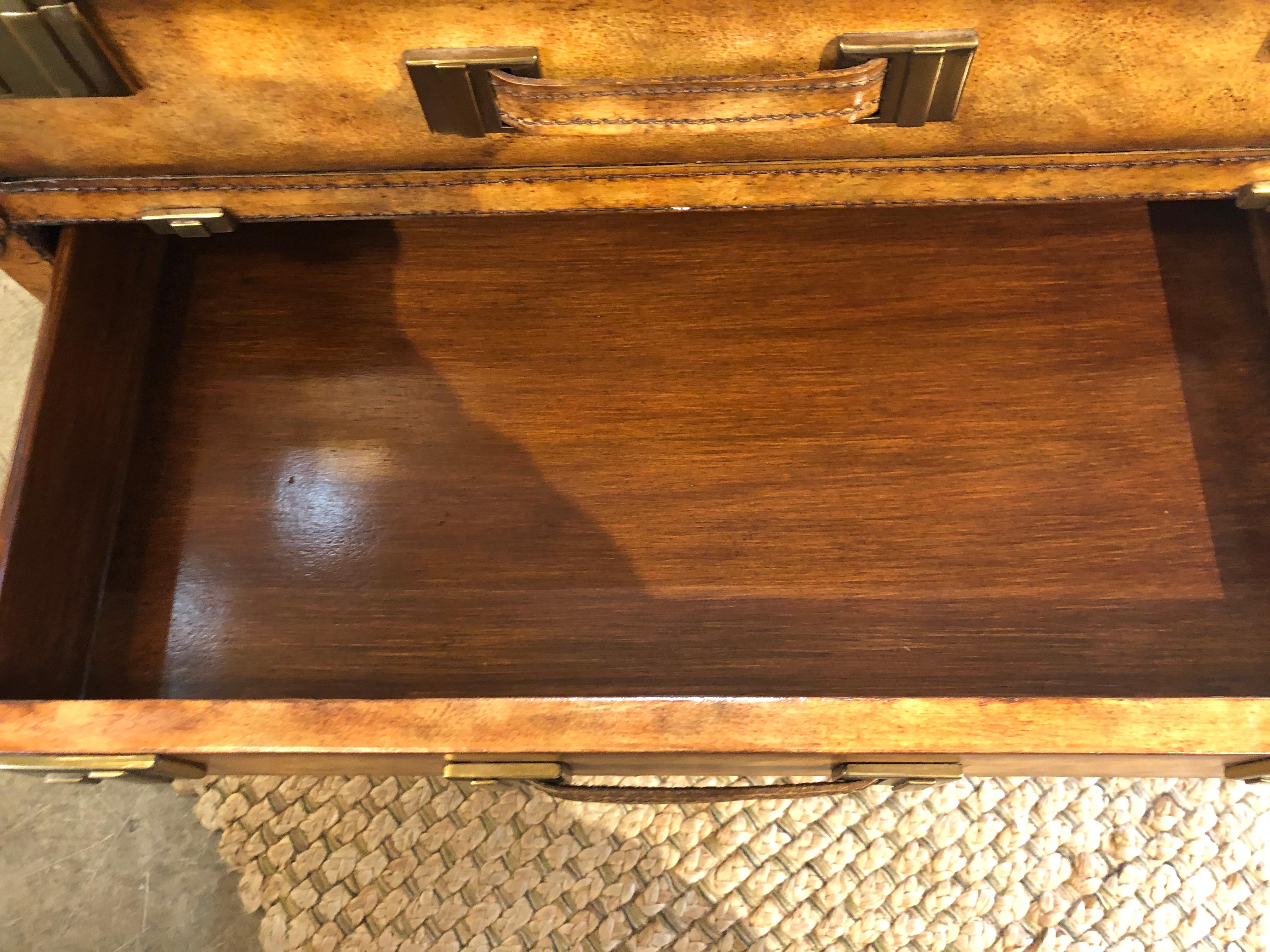 Leather and brass clad suitcase style chest of drawers by Maitland Smith having 4 drawers with gold foil Maitland Smith label. All upon bun feet.