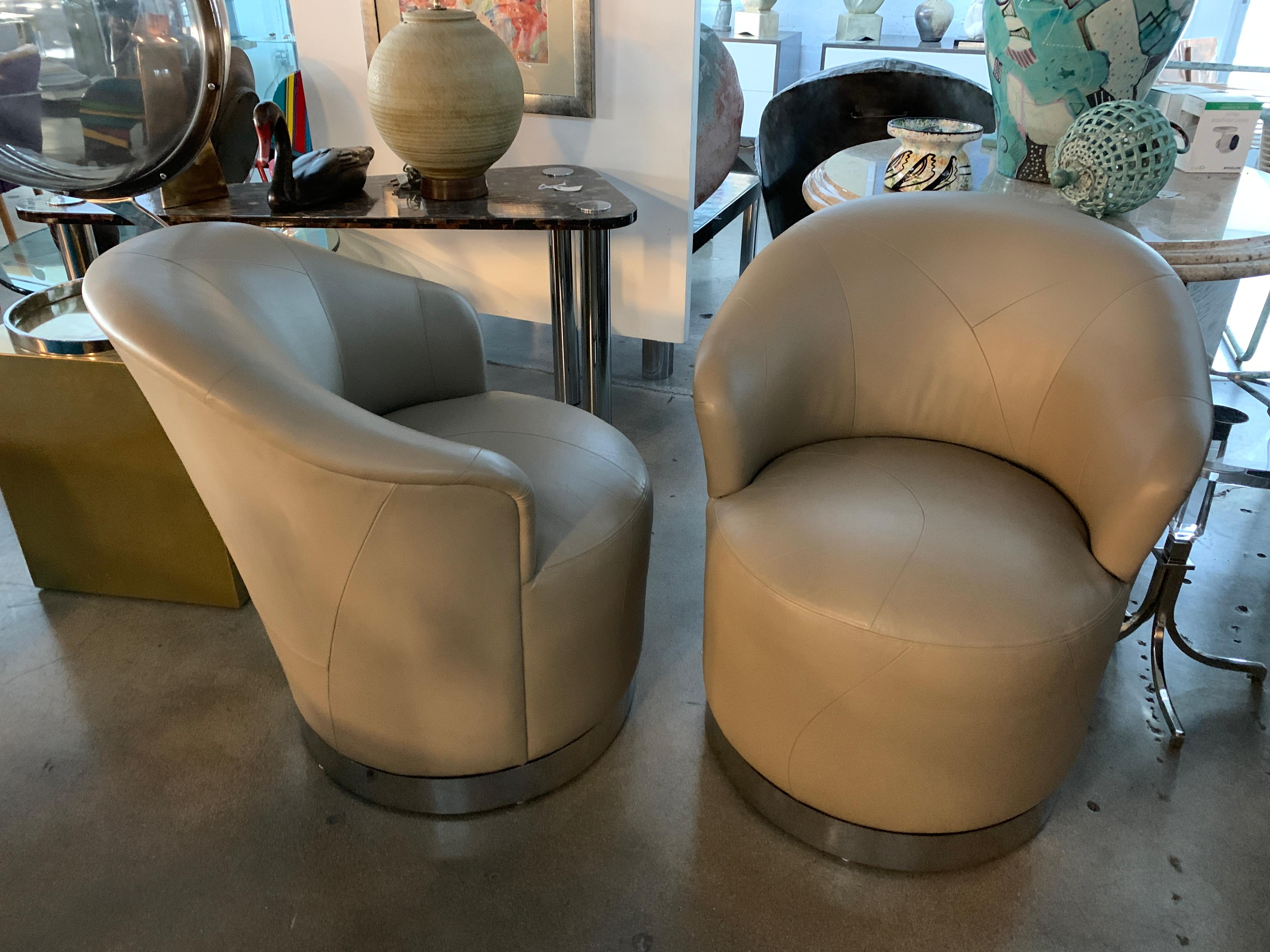 A nice pair of leather swivel chairs with chrome bases by J Robert Scott. Nice pattern to the leather stitching. There are some marks to the Chromes bands and some minor indentations to the chair back.